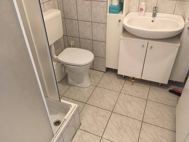 Kleines Badezimmer mit WC, Waschbecken und Duschkabine.