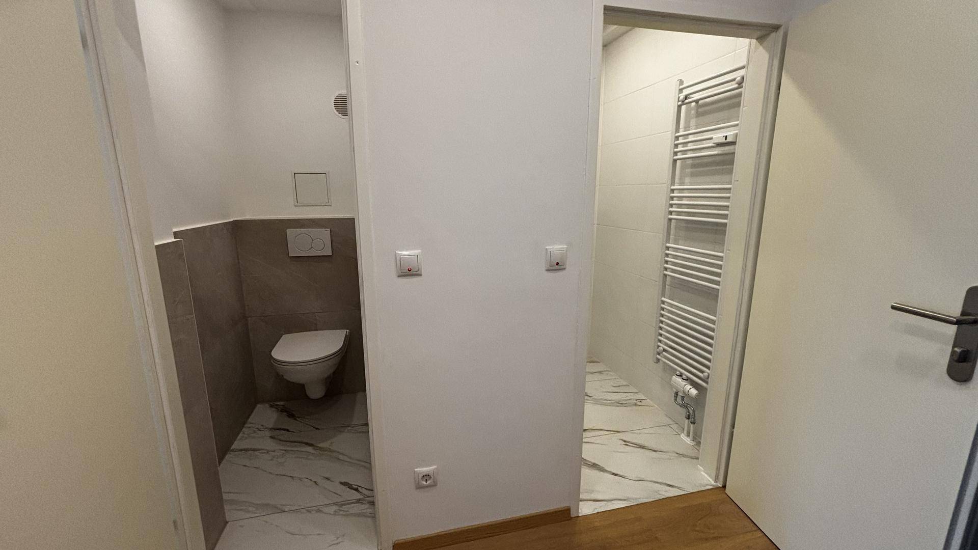 Blick in separate Bereiche für WC und Dusche, beide mit modernen Fliesen ausgestattet.