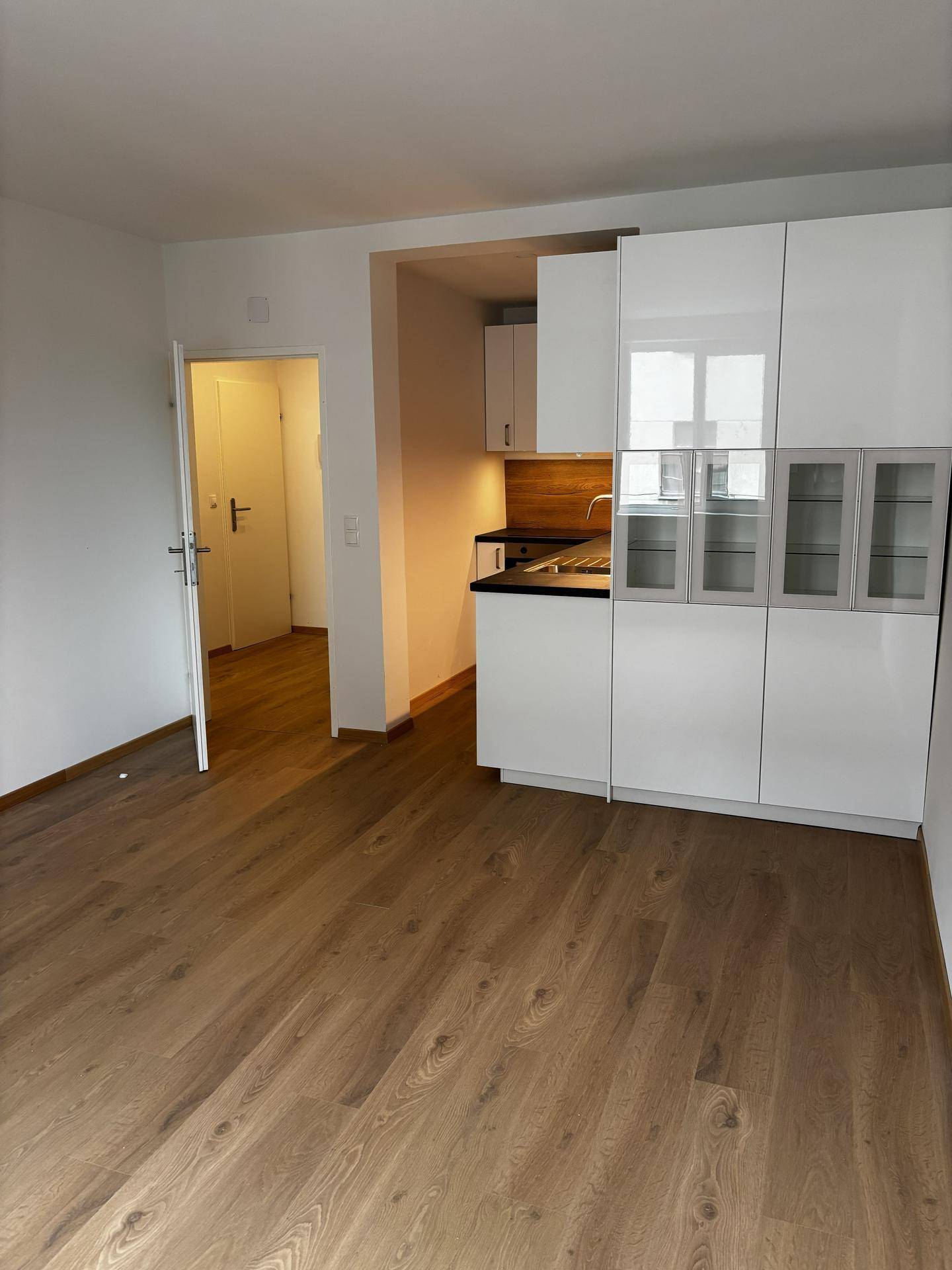 Offener Wohnbereich mit integrierter, moderner Küchenzeile und Holzboden.