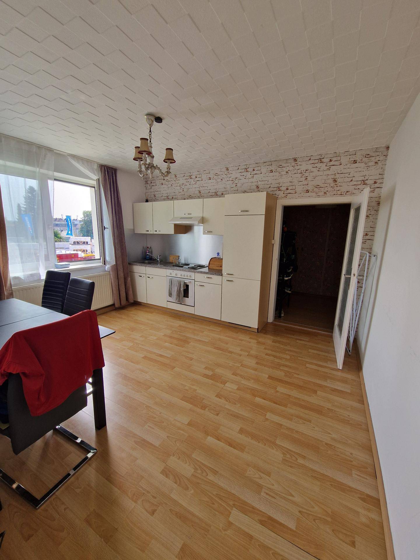Helle Küche mit integriertem Essbereich, Laminatboden und weißen Einbauschränken.