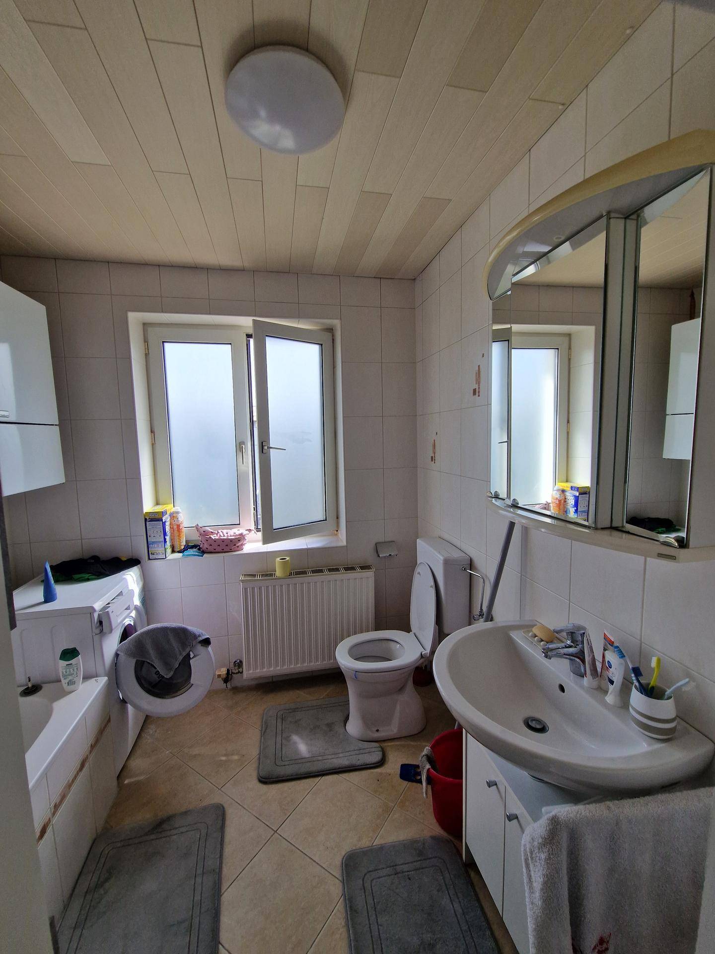 Funktionales Badezimmer mit Badewanne, WC, Waschbecken und Fenster für Tageslicht.