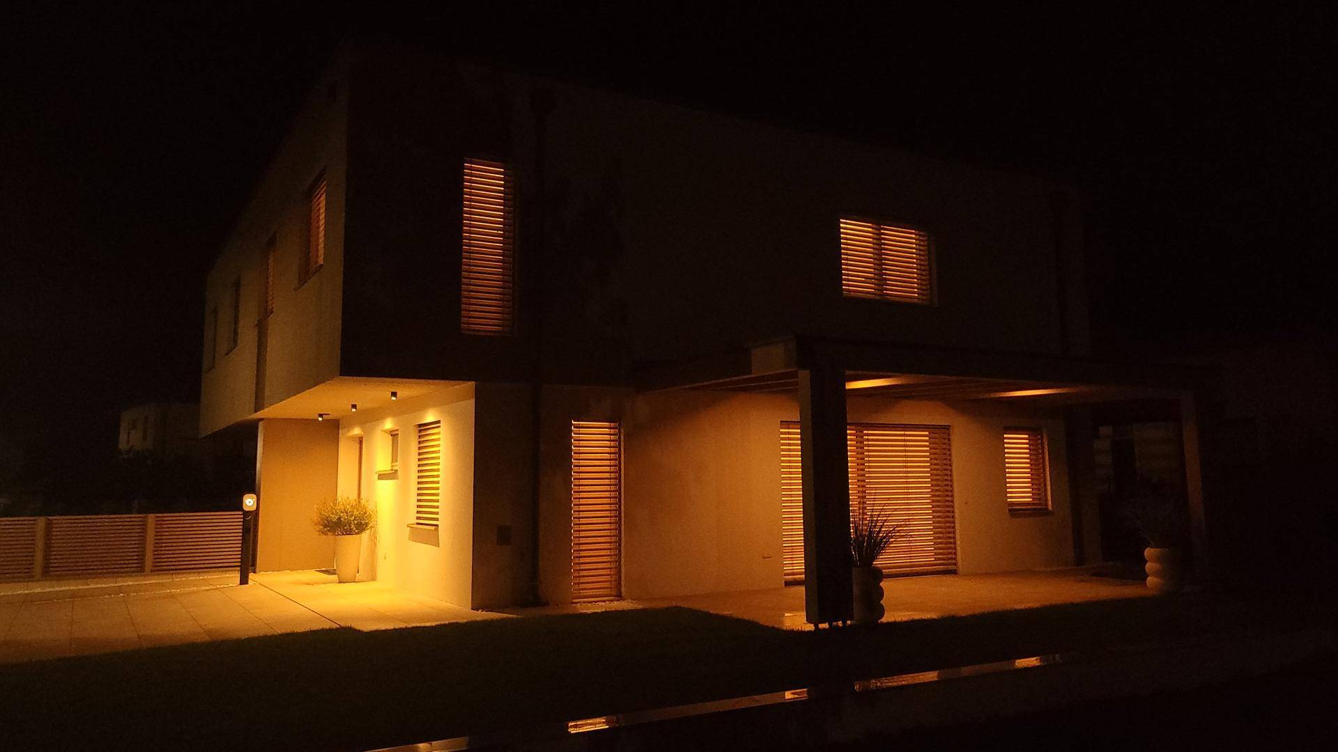 Beleuchtete Fassade des modernen Hauses in der Nacht mit warmem Lichtschein.