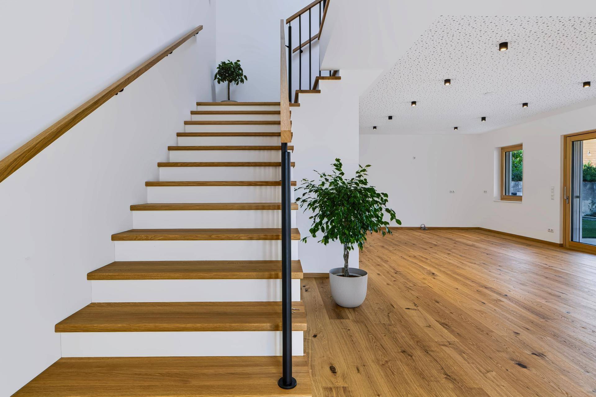 Elegante Holztreppe mit modernem Geländer, die den Wohnbereich mit dem Obergeschoss verbindet.