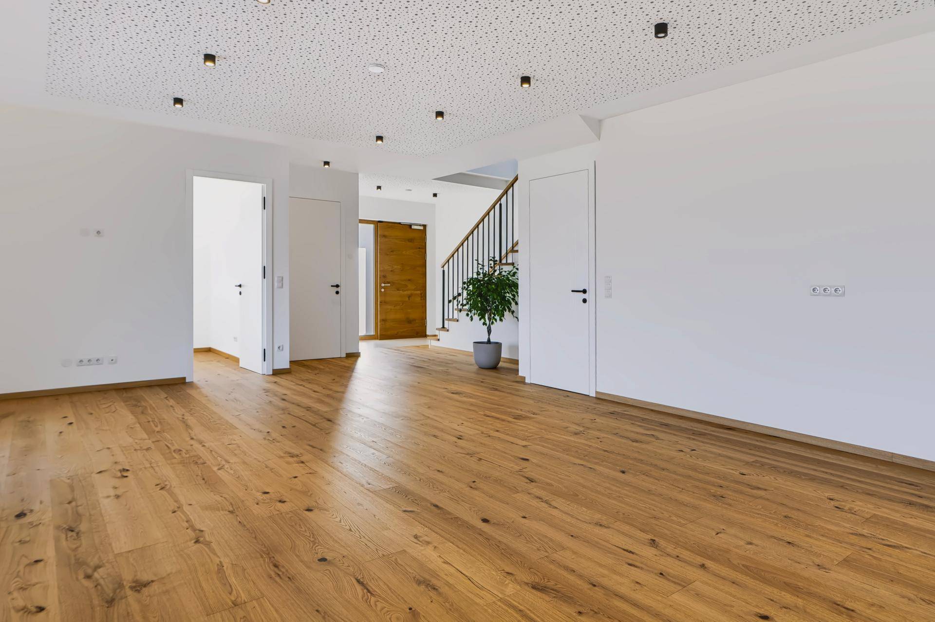 Heller, offener Wohnbereich mit Eichenparkettboden und moderner Deckenbeleuchtung.