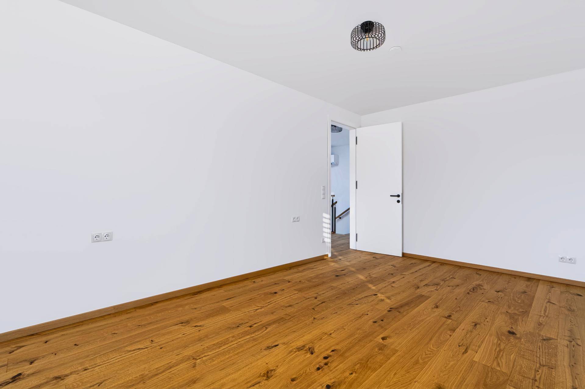 Modernes Schlafzimmer mit Eichenparkett und weißer Tür, bereit für individuelle Gestaltung.