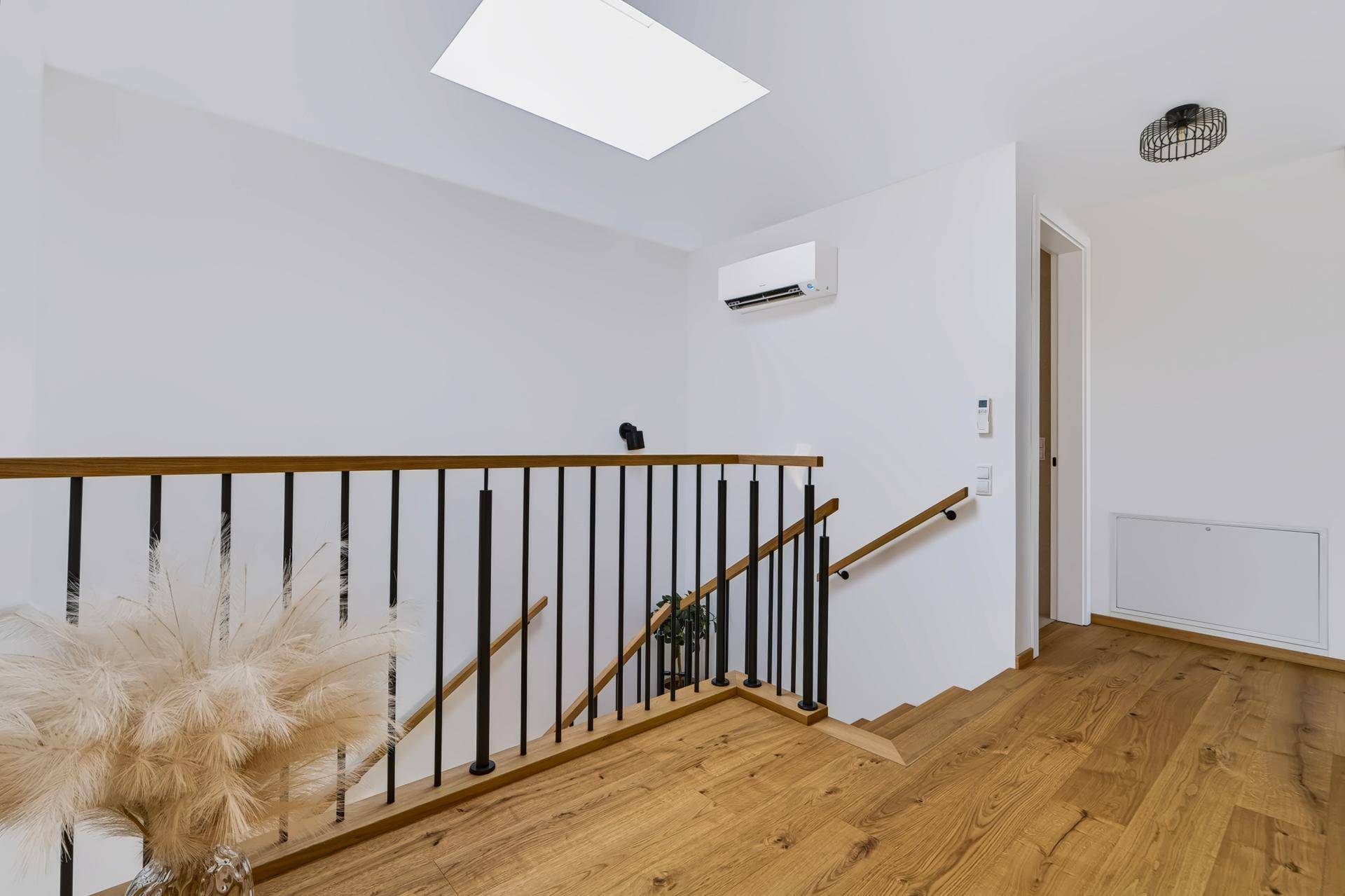 Heller Flur im Obergeschoss mit Treppengeländer, Dachfenster und Klimaanlage.