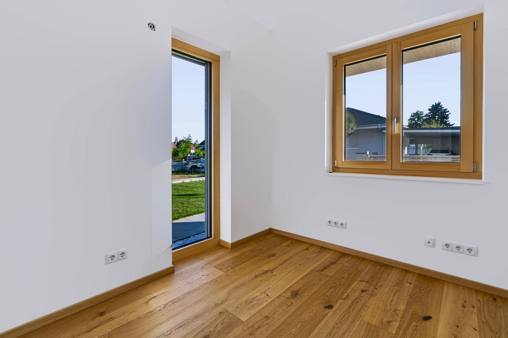 Helles Zimmer mit Holzboden und großen Fenstern, ideal als Büro oder Gästezimmer.