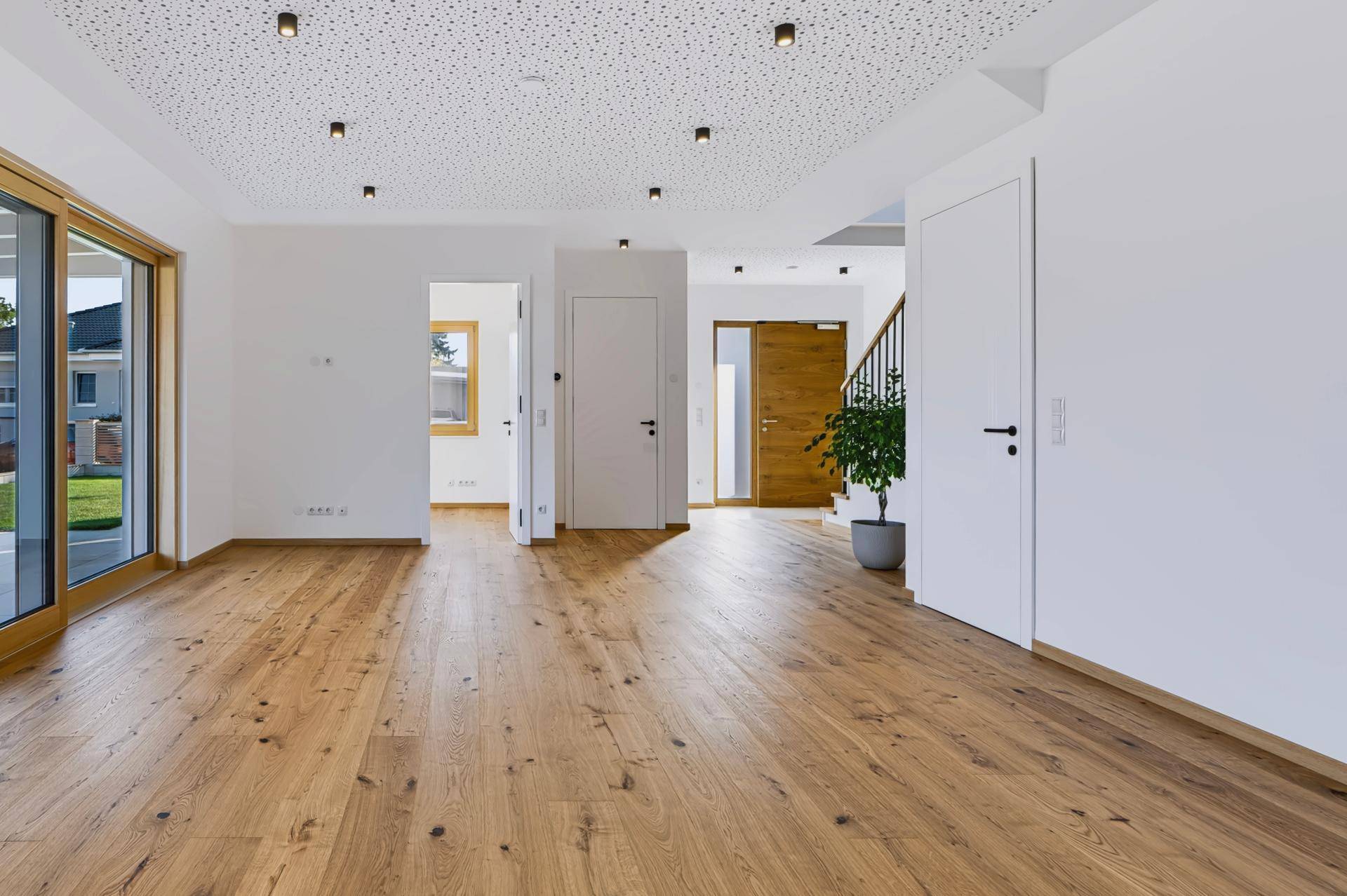 Offener Wohnbereich mit Holzboden, weiß gestrichenen Wänden und Blick auf den Eingangsbereich.