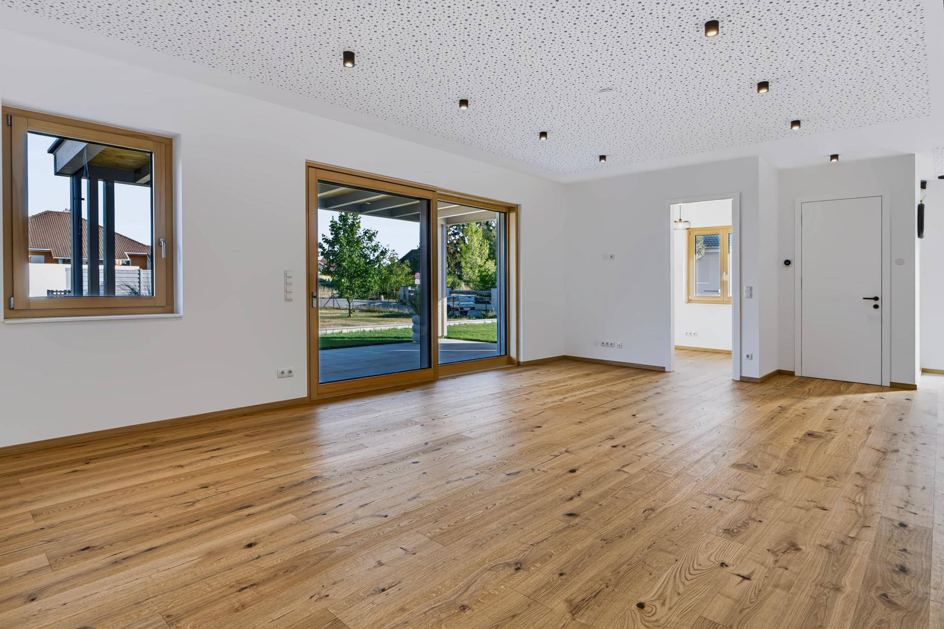 Geräumiger Wohnbereich mit großen Schiebetüren zum Garten und hellem Eichenparkett.
