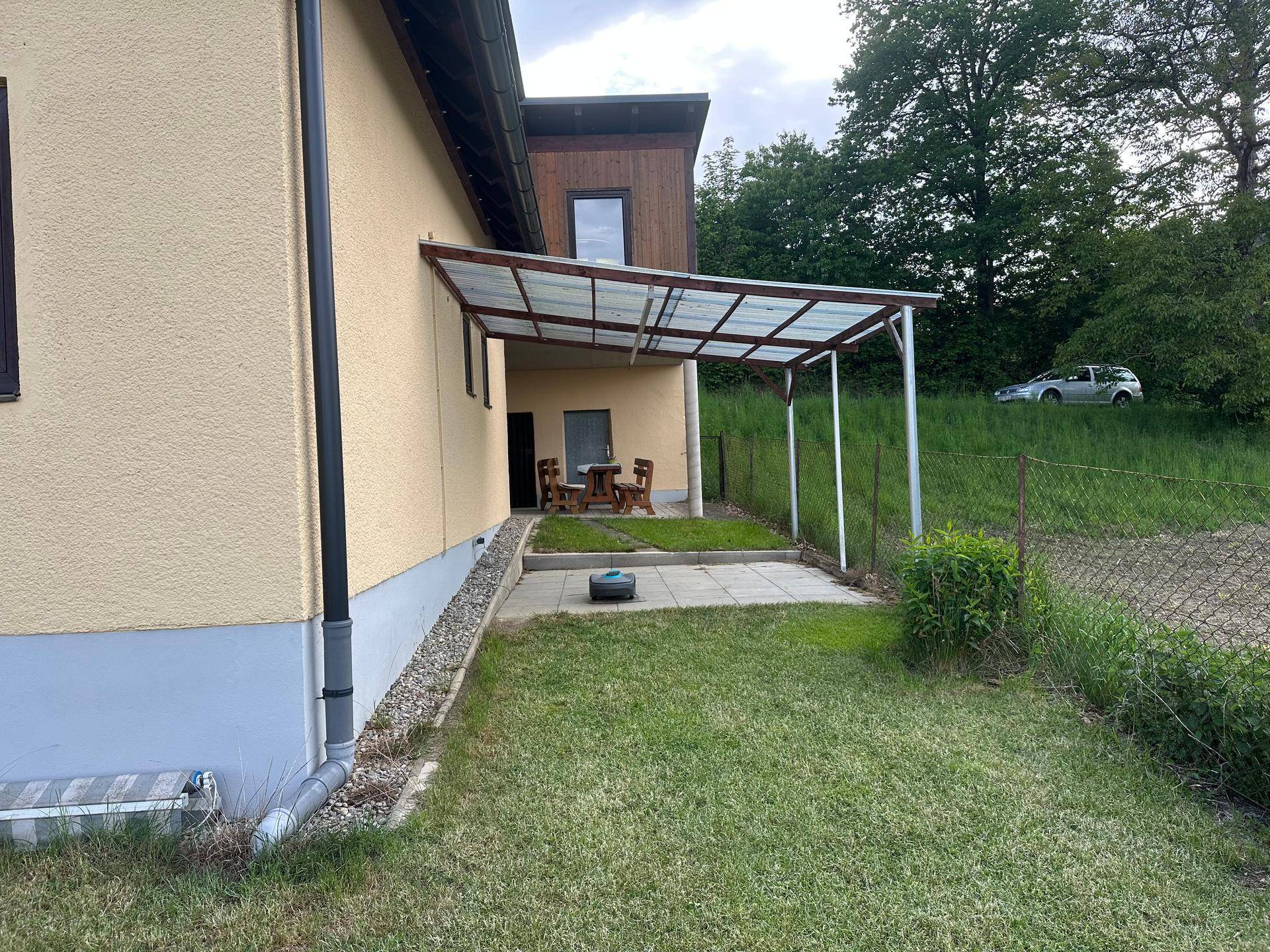 Überdachte Terrasse mit Gartenmöbeln und Zugang zum Rasenbereich des Gartens.