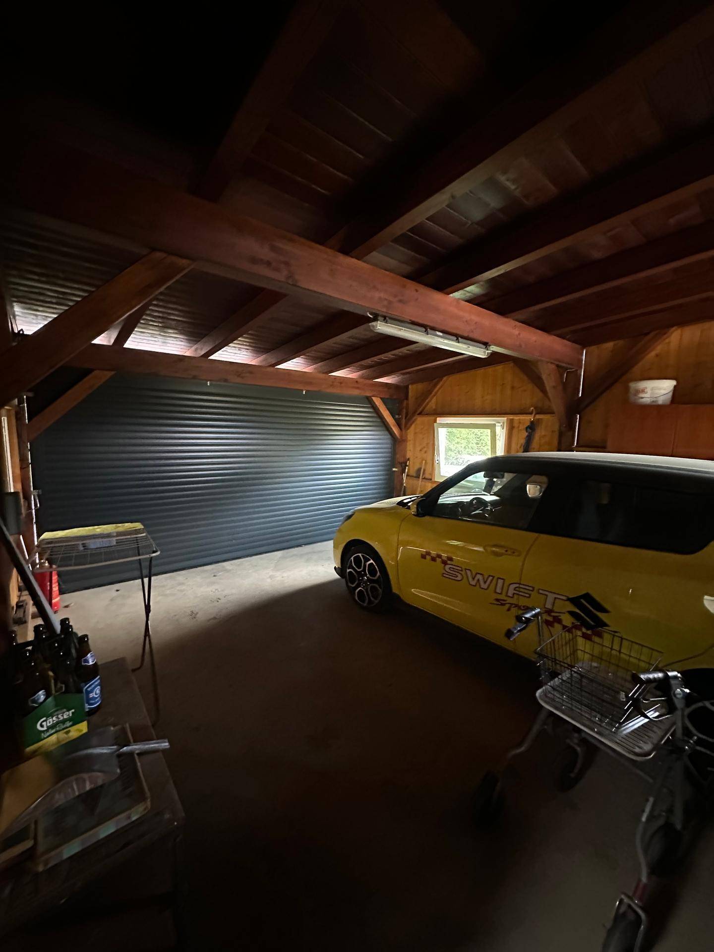Geräumige Garage mit Holzbalken und einem geparkten Auto, bietet viel Platz.