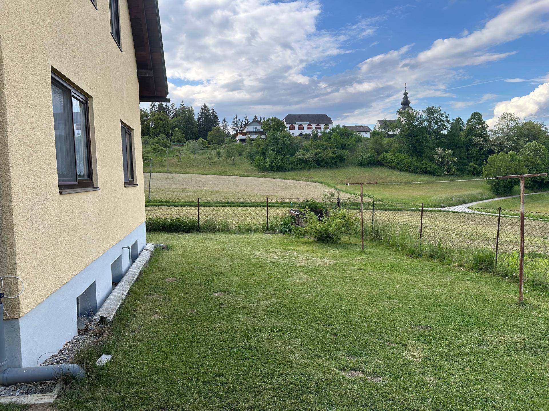 Seitlicher Gartenbereich mit Rasenfläche und weitem Blick auf die umliegende Landschaft.