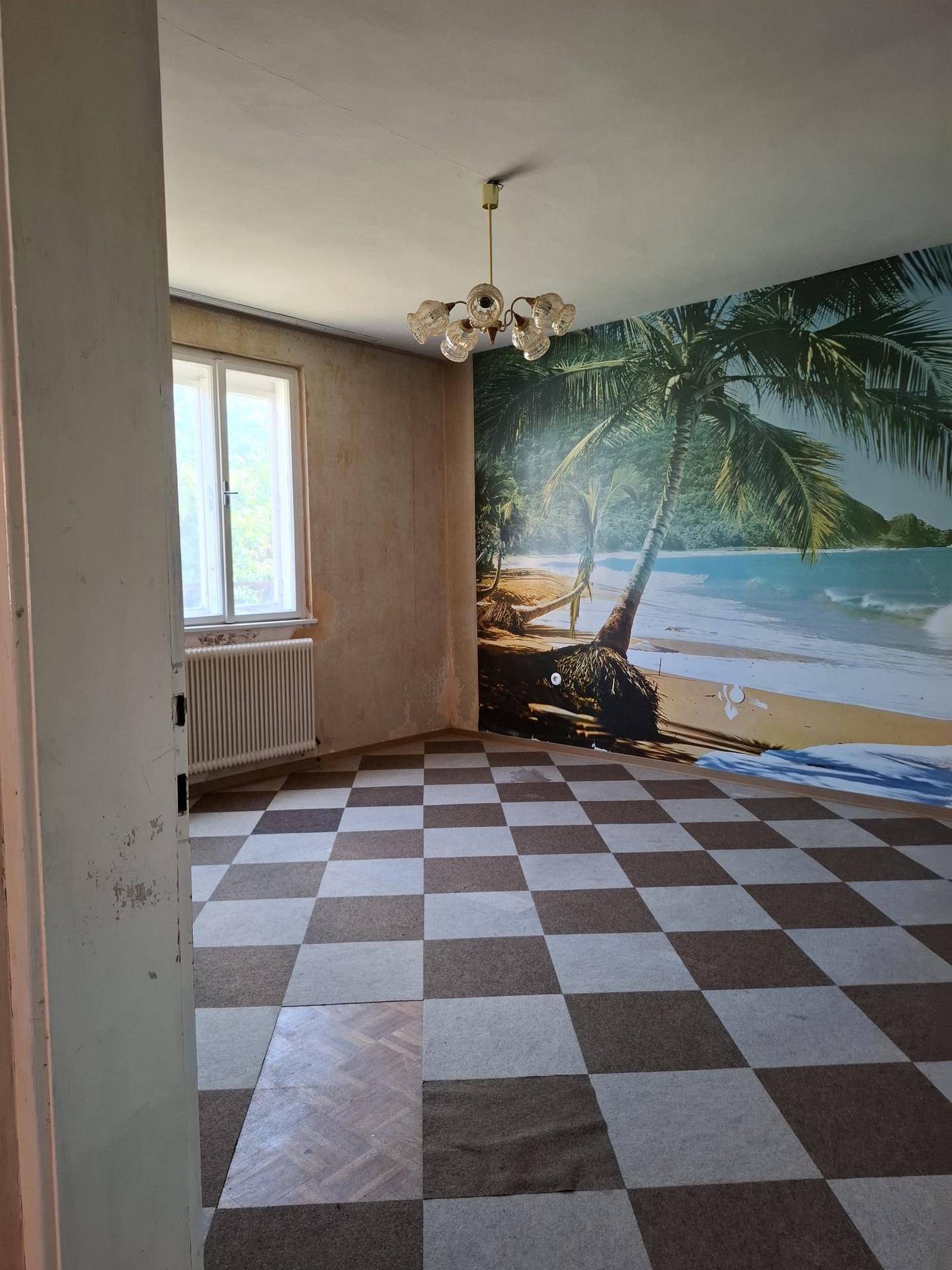 Geräumiger Raum mit auffälliger Strandtapete, kariertem Boden und viel Tageslicht.