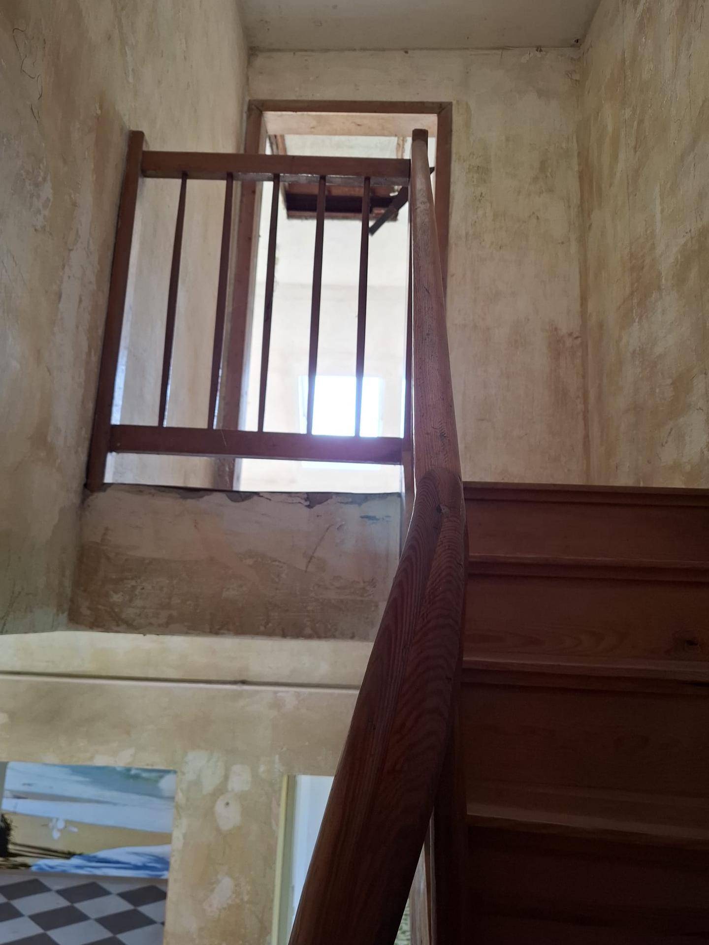 Holztreppe mit Geländer in einem Flur, der auf eine Renovierung des gesamten Bereichs hindeutet.