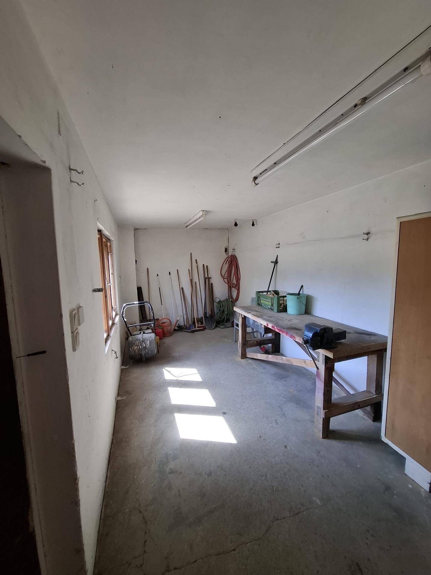 Geräumiger Werkstattraum mit einer stabilen Werkbank, Werkzeugen und einem robusten Betonboden.