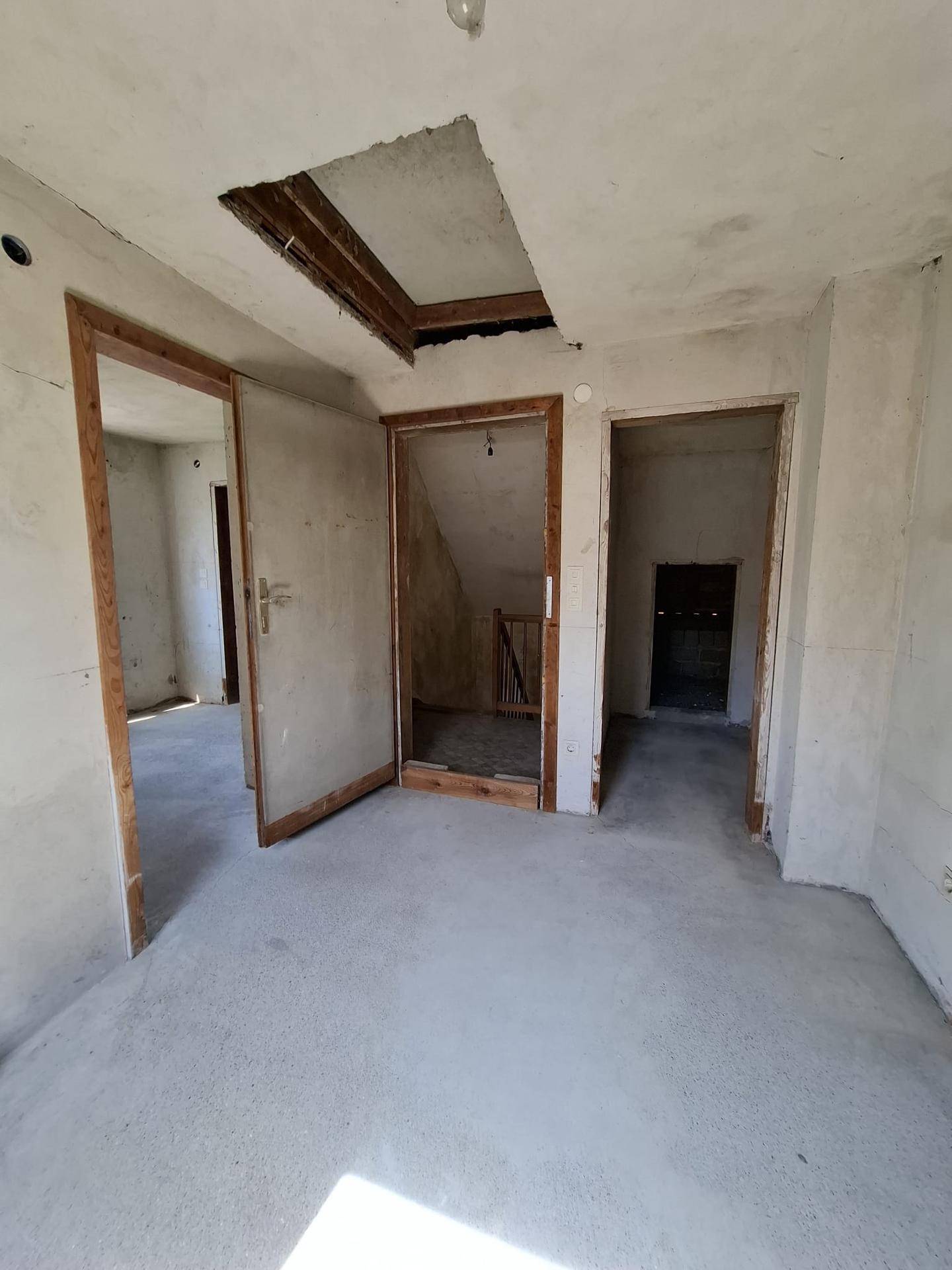 Unfertiger Raum mit Betonboden und mehreren Türöffnungen, der auf den Ausbau wartet.