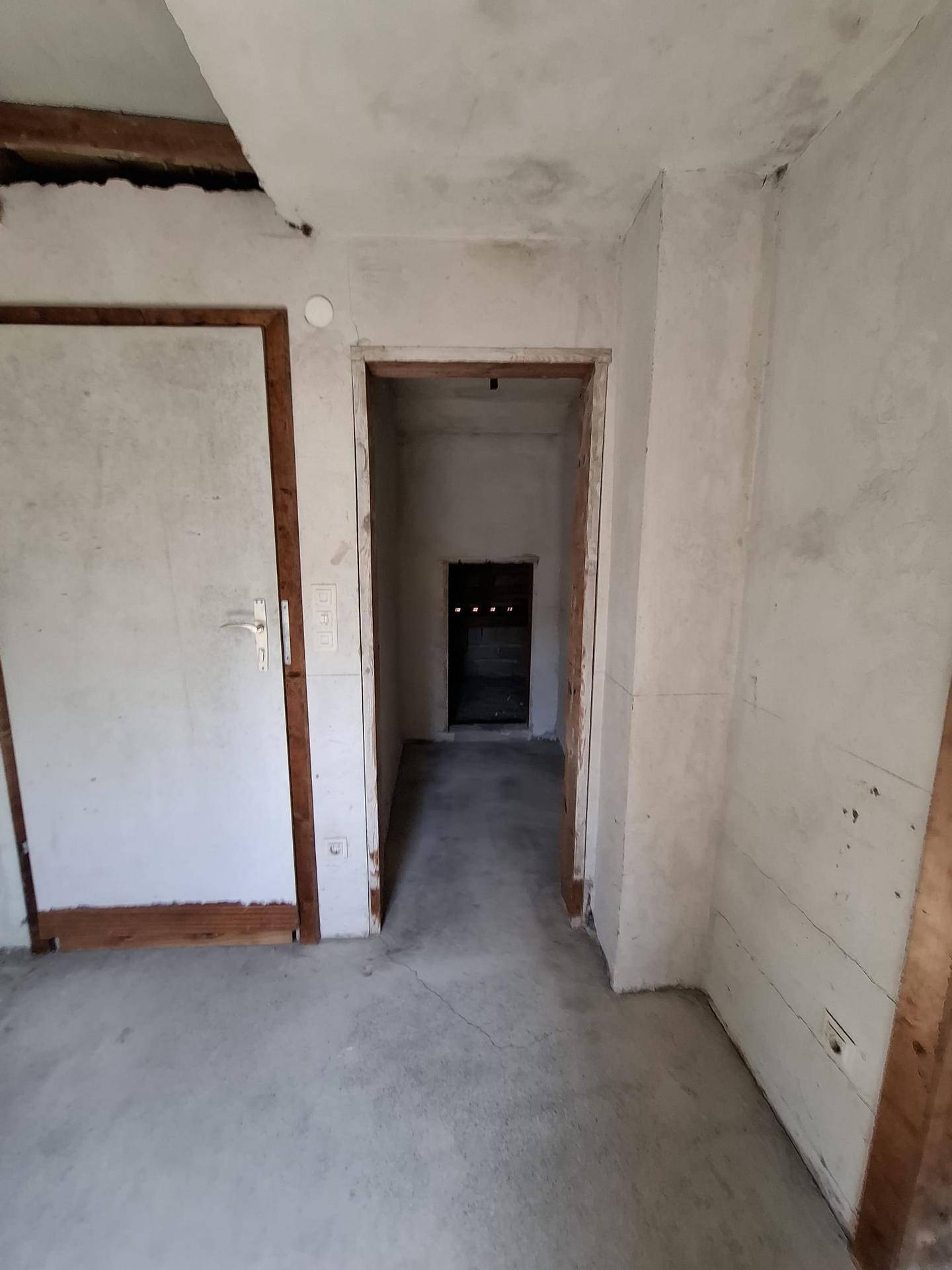 Unfertiger Innenraum mit Betonboden und Türrahmen, bereit für den weiteren Ausbau.
