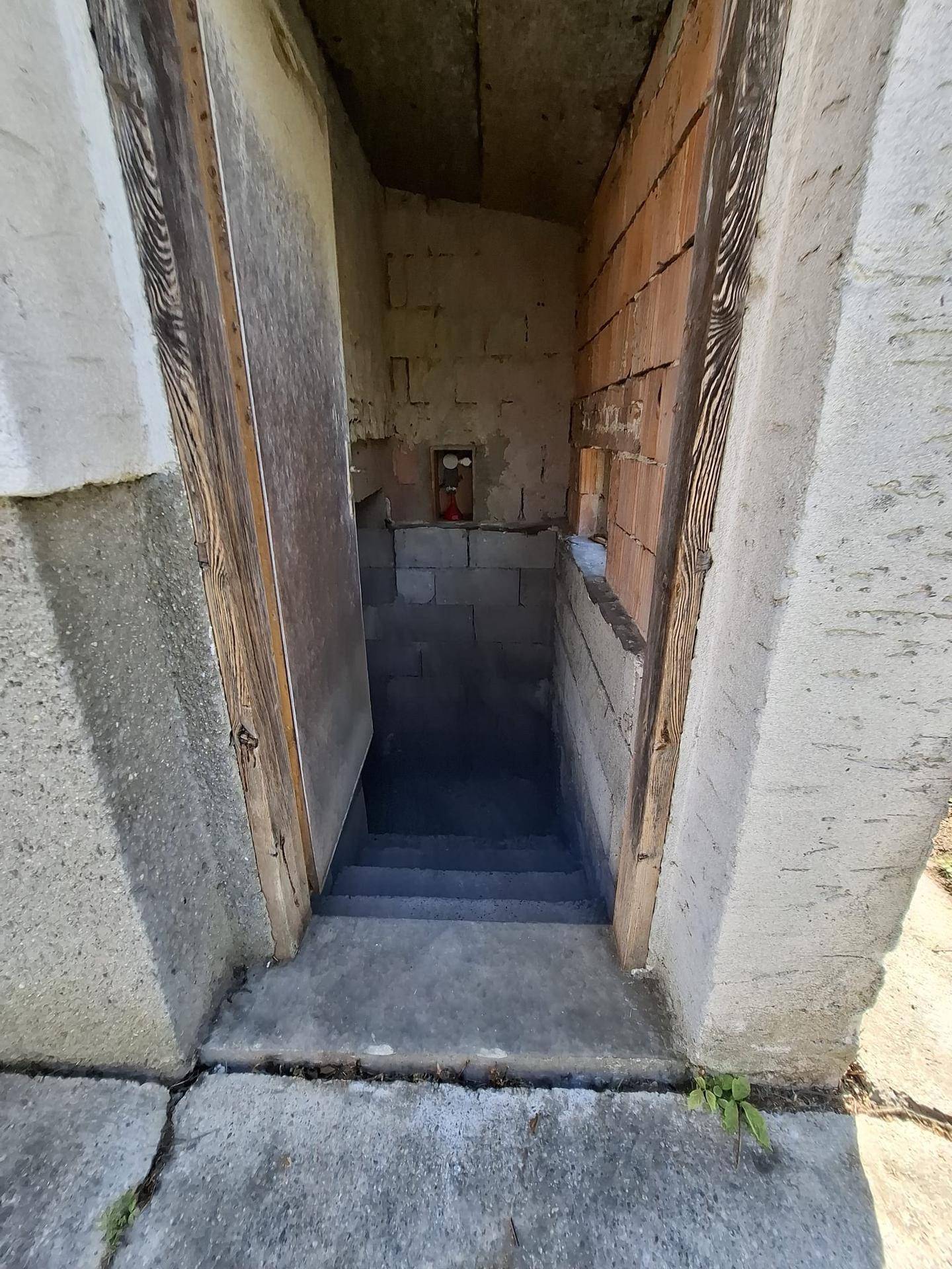 Eingangsbereich mit Treppe, die in einen Keller oder Untergeschoss des Gebäudes führt.