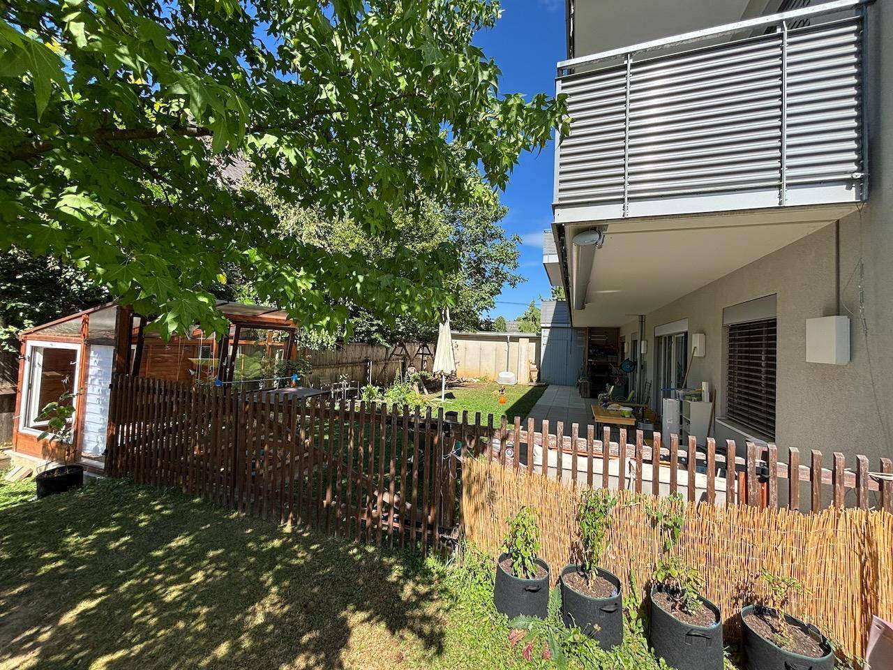 Großer Gartenbereich mit Terrasse, Balkon und Blick auf das Gebäude.