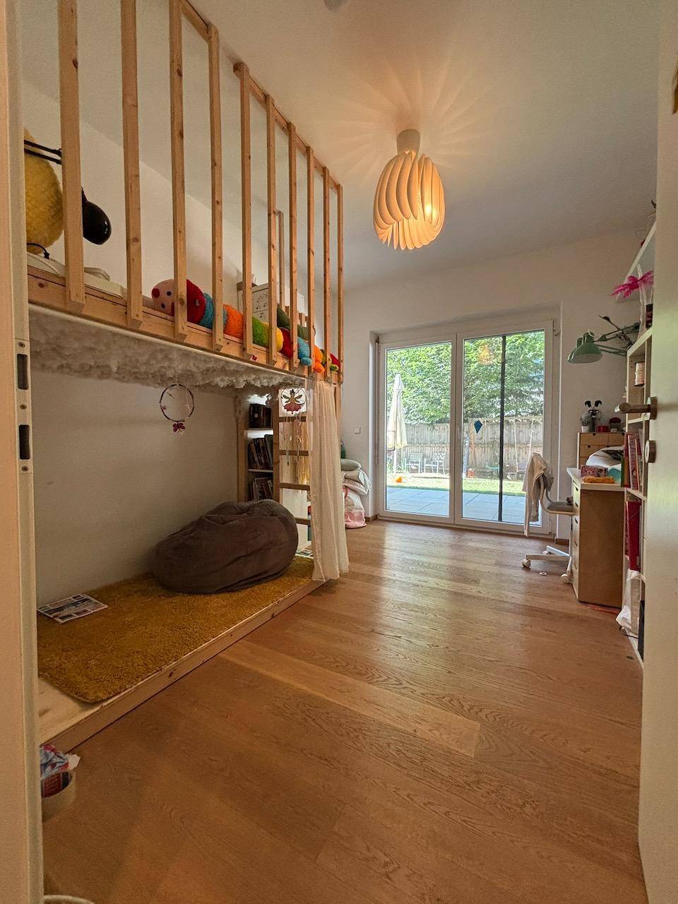 Geräumiges Kinderzimmer mit Hochbett, Sitzsack und Zugang zum Garten.