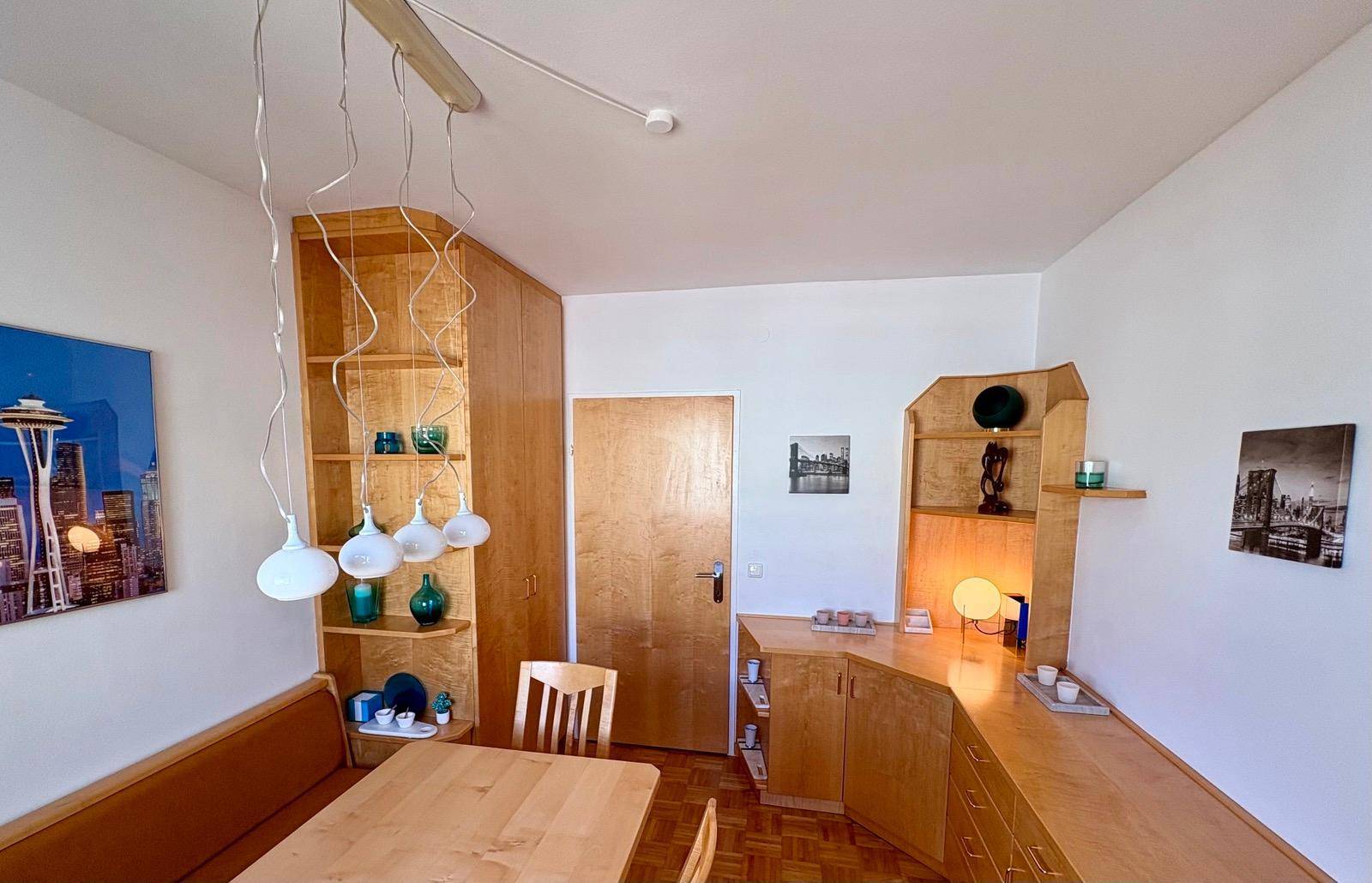 Essbereich mit Holztisch, Eckbank und integrierten Holzregalen.