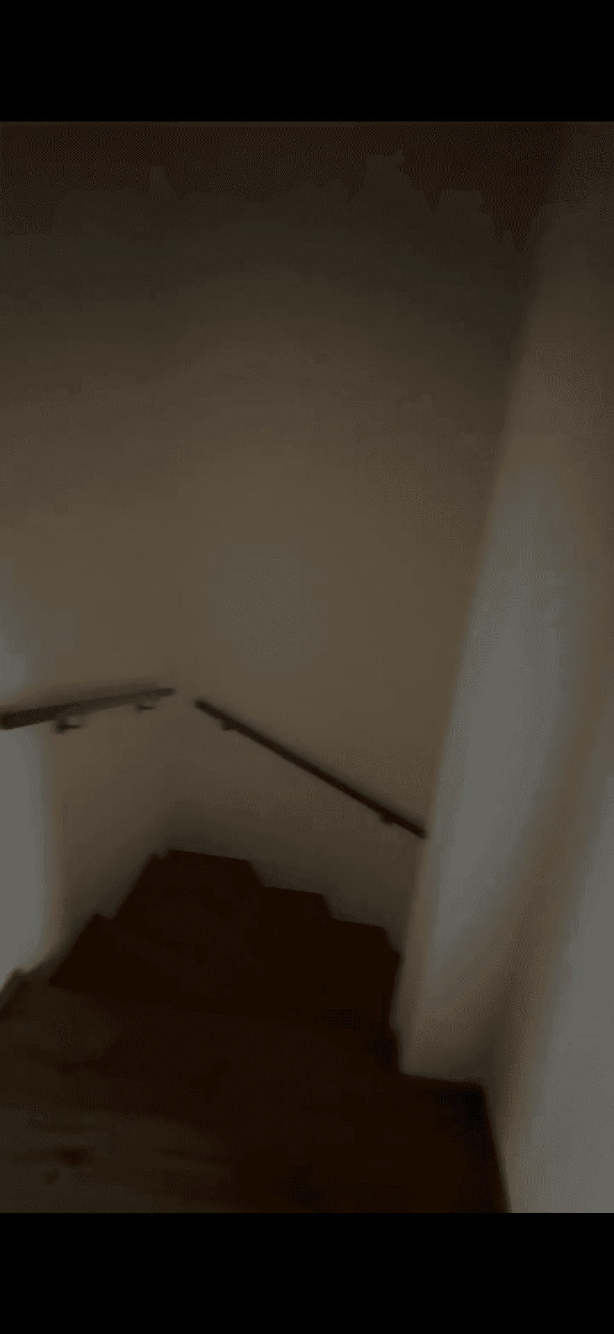 Treppenhaus mit Holzstufen und einem schlichten Handlauf, der die Etagen verbindet.