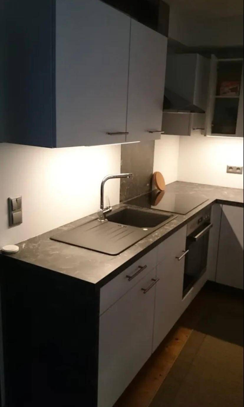 Moderne Küche mit weißen Oberschränken, dunkler Arbeitsplatte und integriertem Kochfeld.