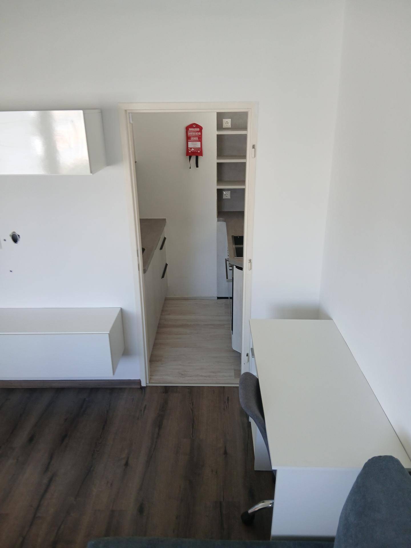 Blick vom Wohnbereich in die kleine, funktionale Küchenzeile mit modernen Oberflächen.