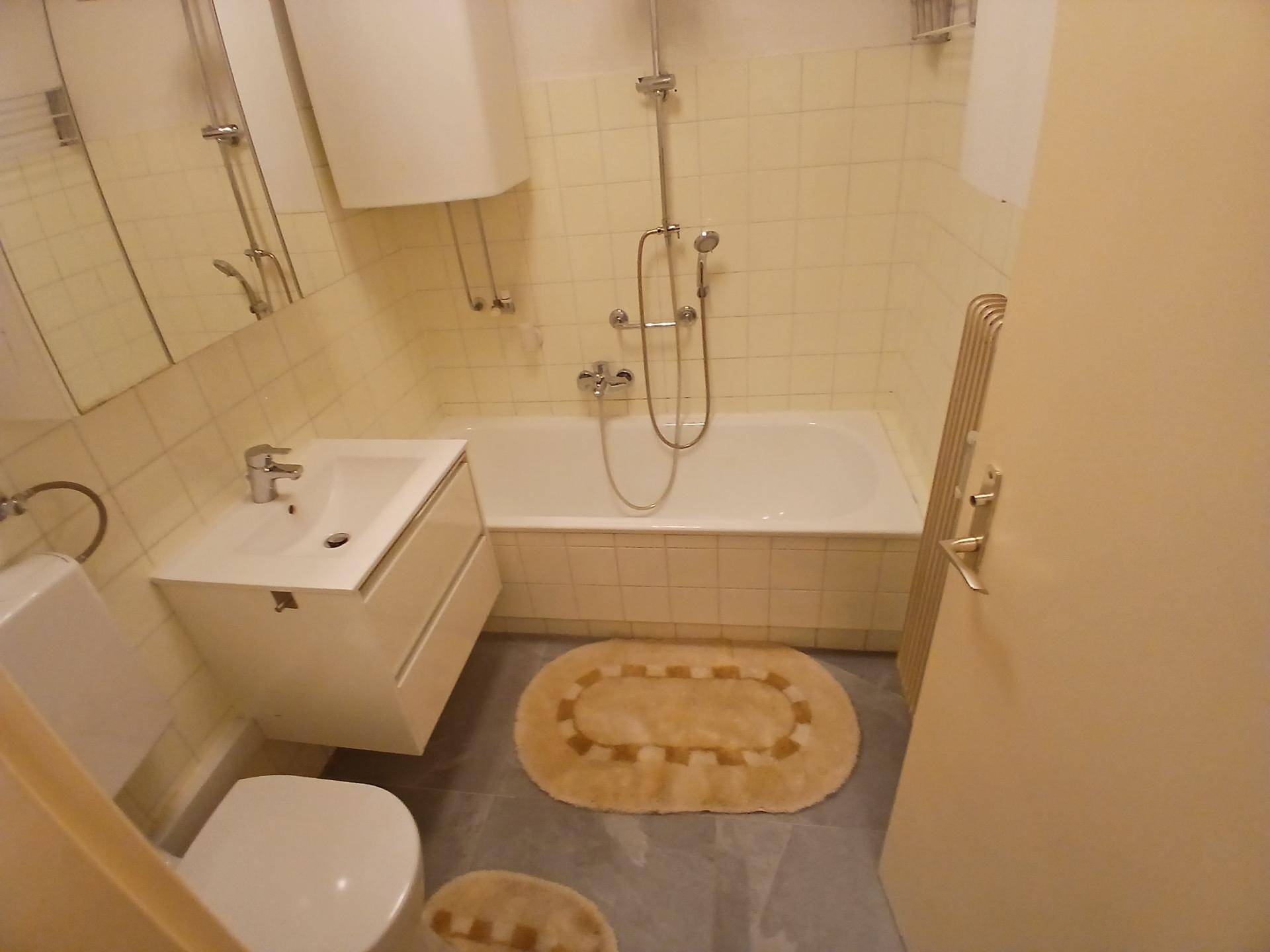 Helles Badezimmer mit Badewanne, Waschbecken und WC, ausgestattet mit gelben Fliesen.