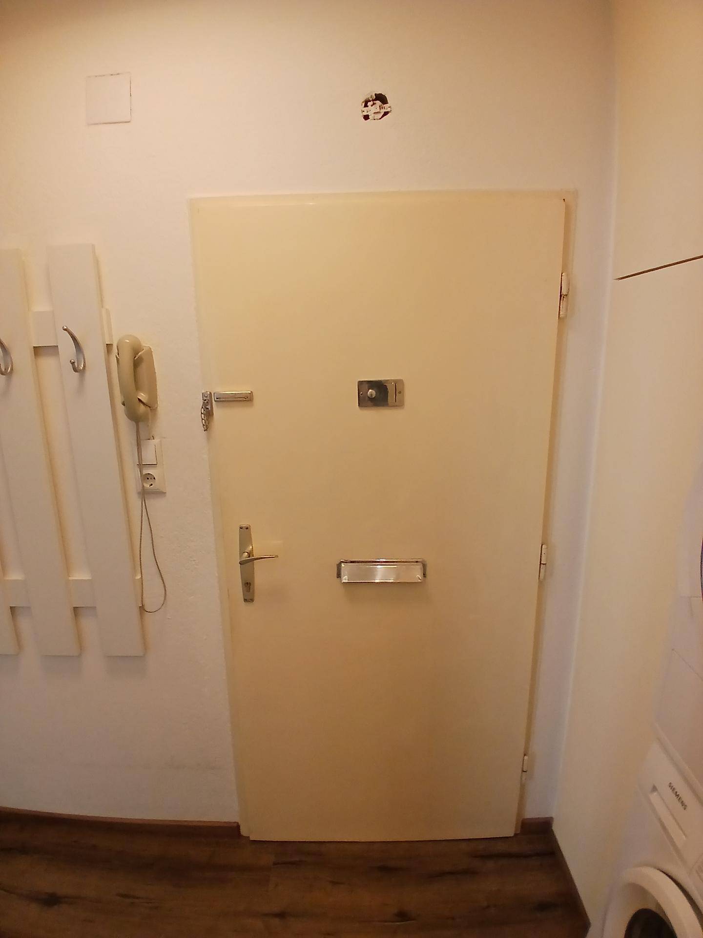 Eingangstür der Wohnung mit Sicherheitsmerkmalen und einem Blick auf die Garderobe.
