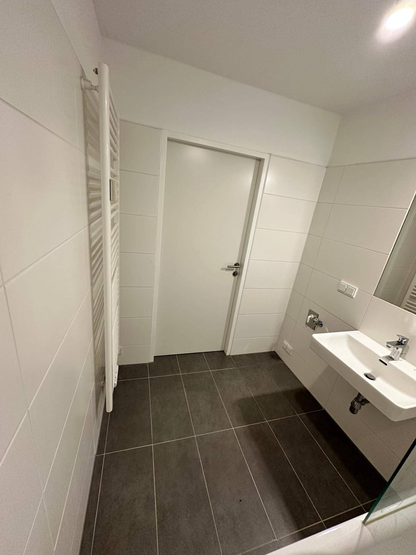 Helles Badezimmer mit Fliesen, Einzelwaschbecken und einem praktischen Handtuchheizkörper.
