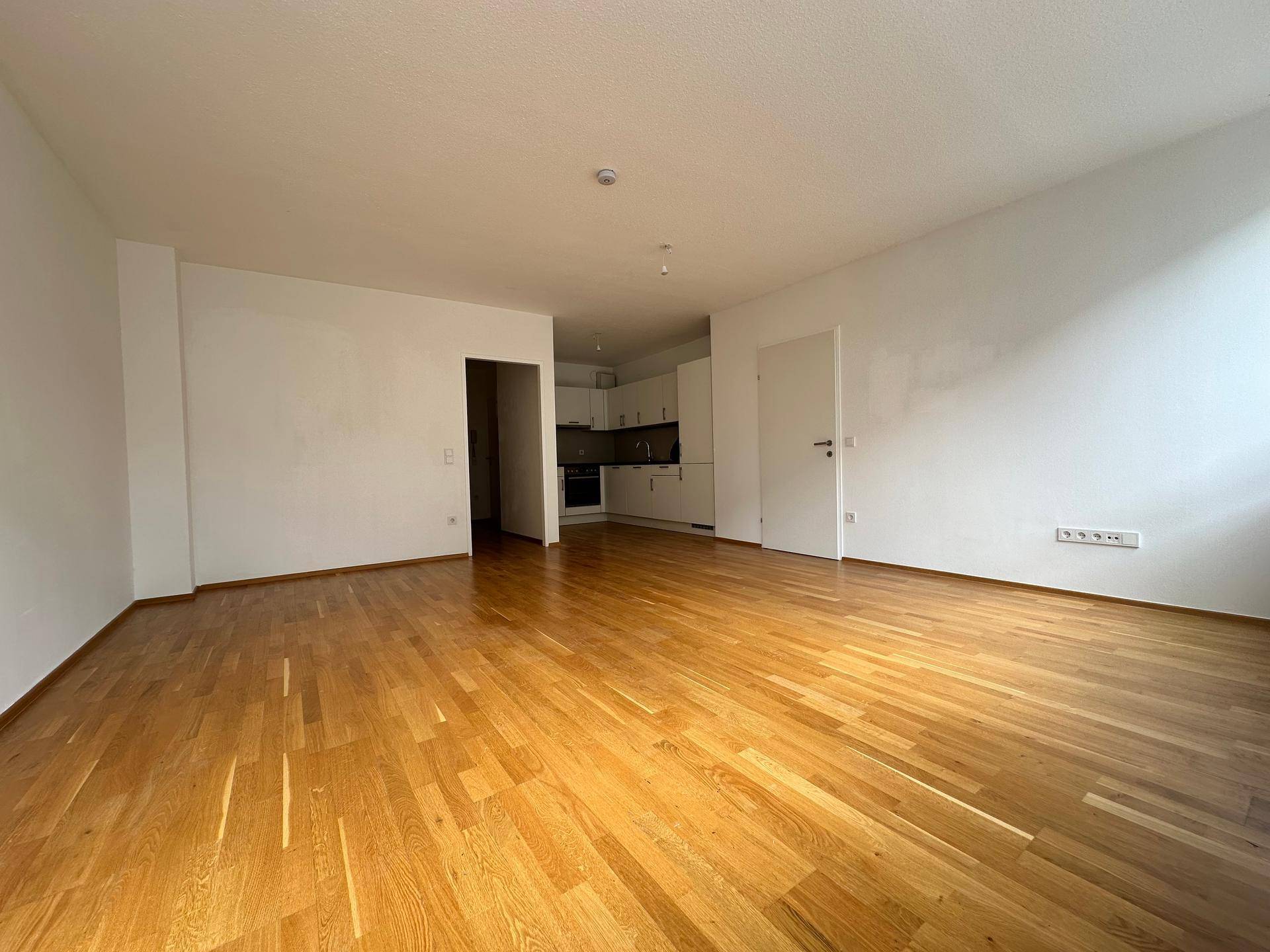 Offener Wohnbereich mit Parkettboden und Blick auf die angrenzende, moderne Küche.