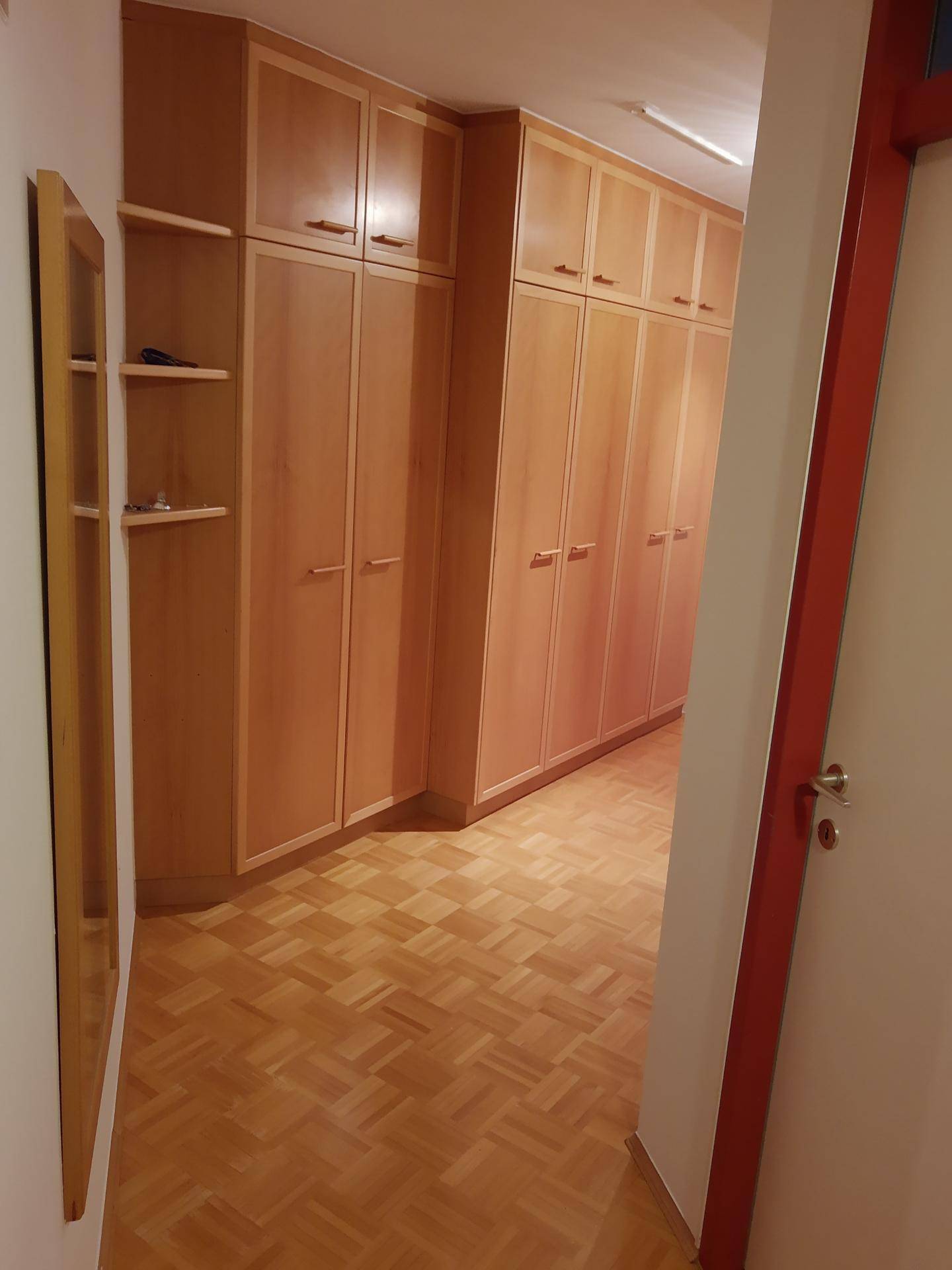 Flur mit praktischen Einbauschränken aus Holz und klassischem Parkettboden.