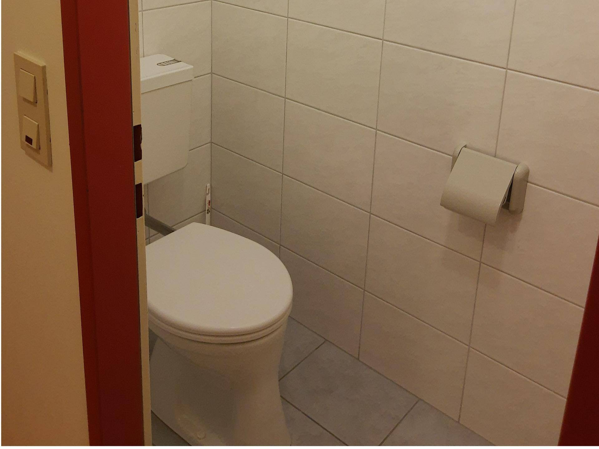 Kleines Gäste-WC mit weiß gefliesten Wänden und einem funktionalen WC.