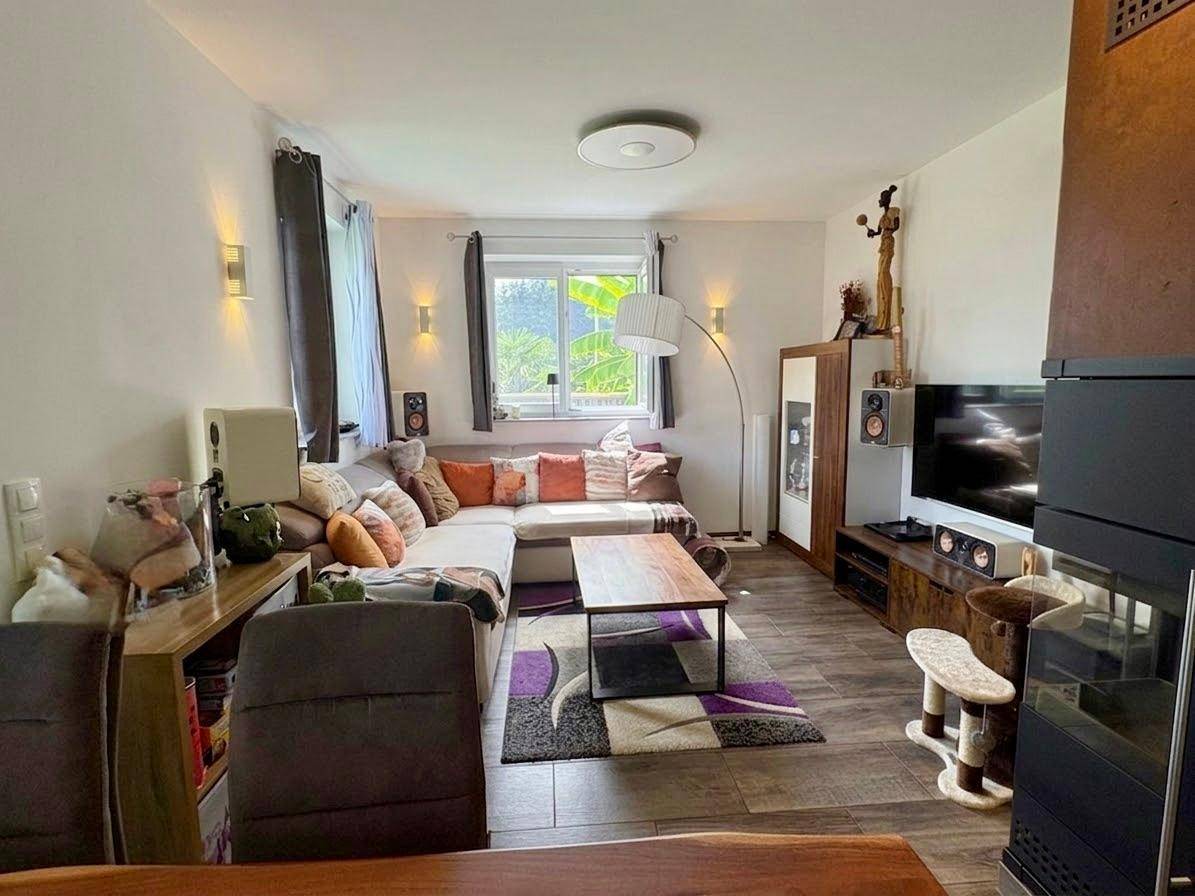Helles Wohnzimmer mit Ecksofa, Couchtisch und Blick in den Garten.