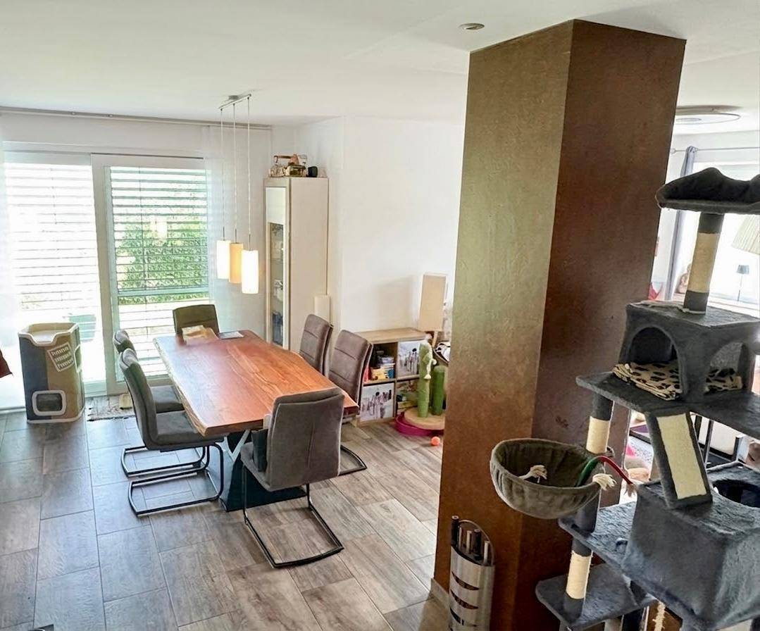 Offener Wohnbereich mit großem Esstisch und Zugang zur Terrasse, verbunden mit der Küche.