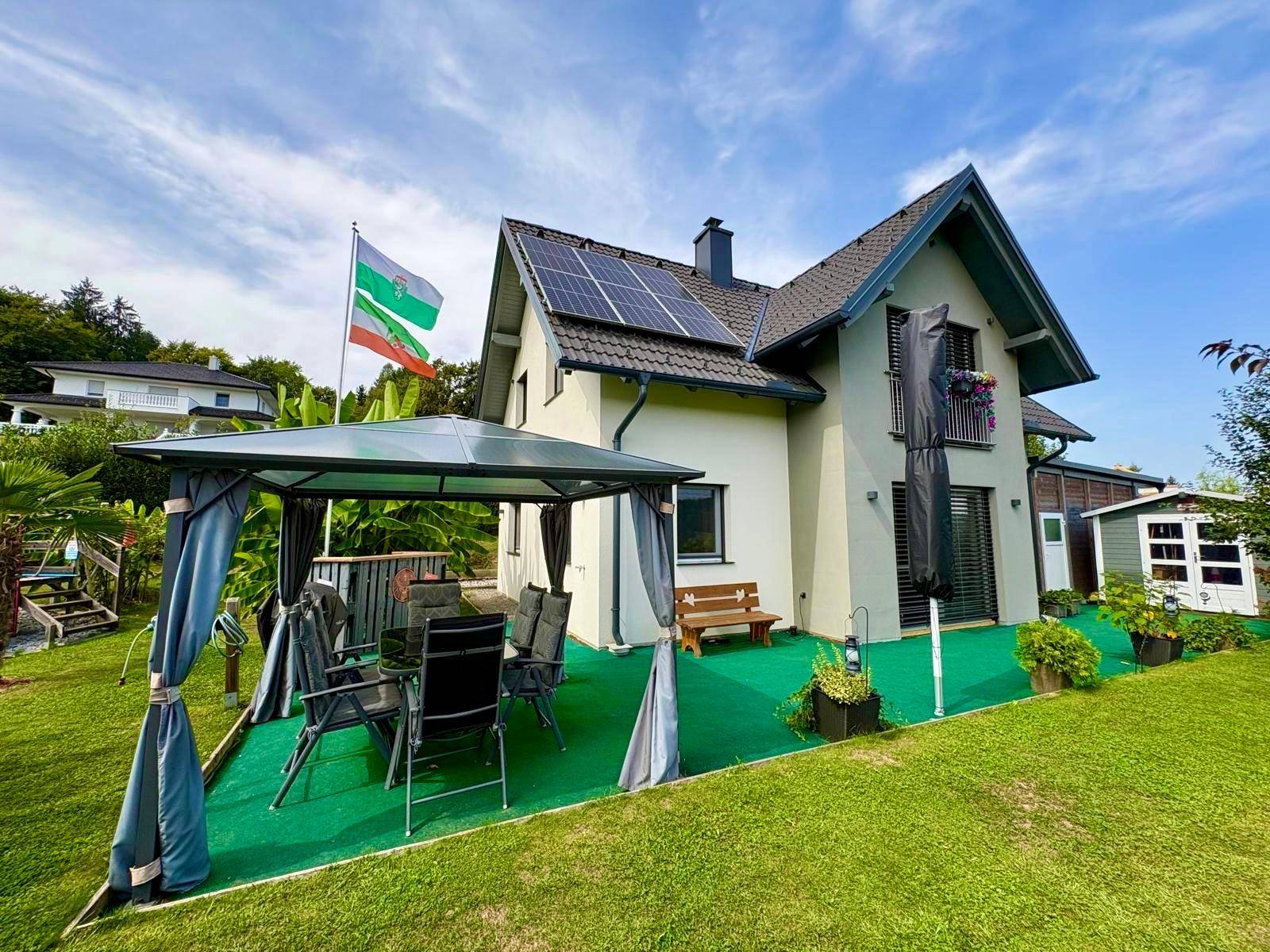 Gepflegter Gartenbereich mit Pavillon, Esstisch und Blick auf das moderne Einfamilienhaus.