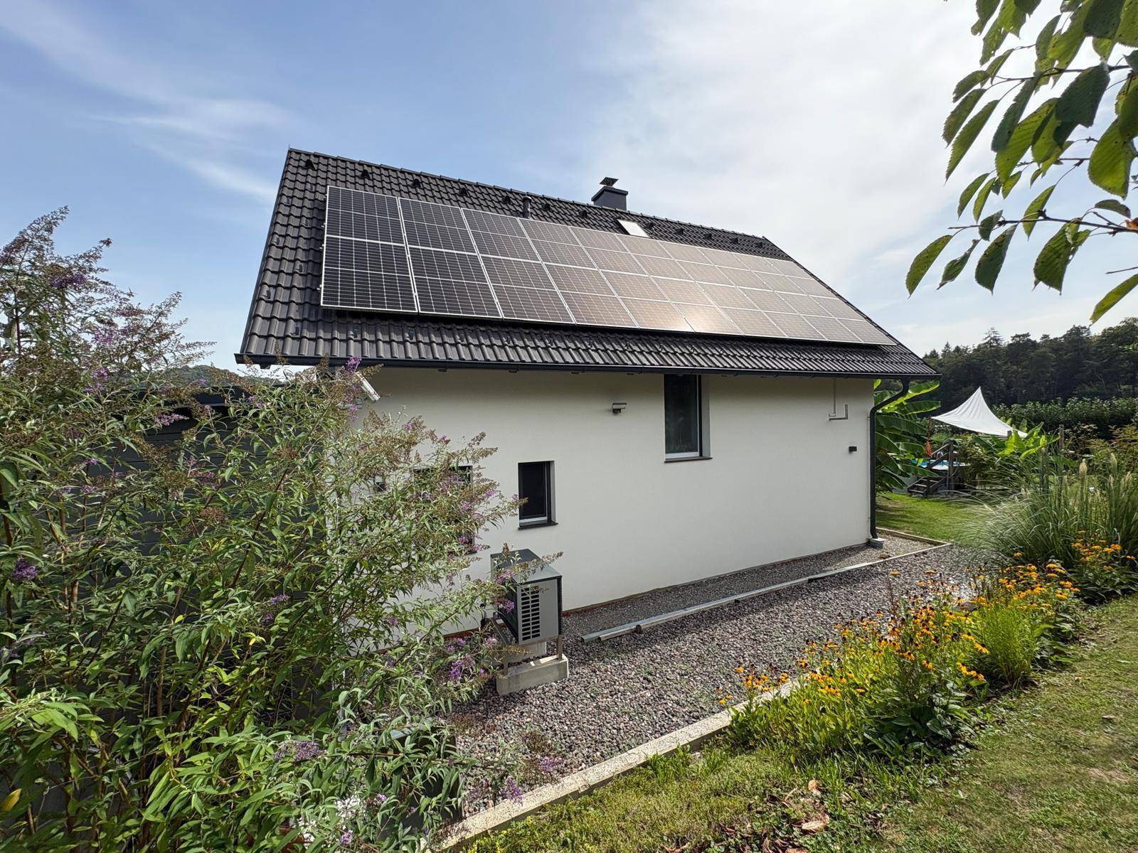 Rückseite des Hauses mit Photovoltaikanlage auf dem Dach und gepflegtem Gartenbereich.