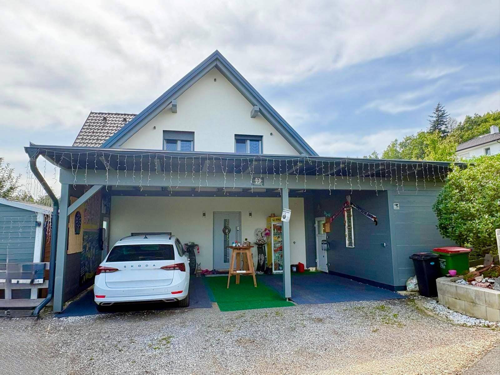 Vorderansicht des Hauses mit großem Carport und geparktem Auto.