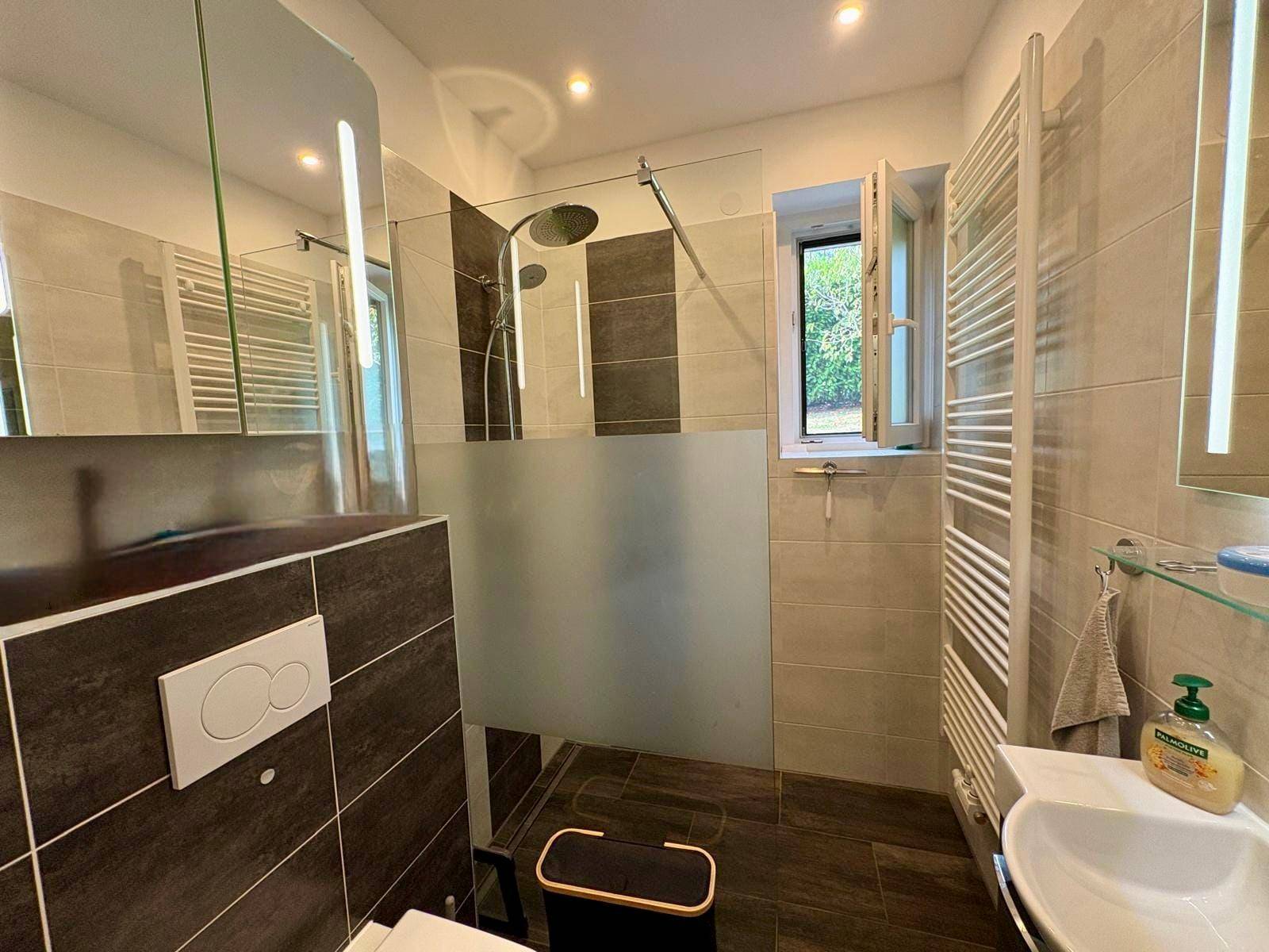 Modernes Badezimmer mit ebenerdiger Dusche, Wand-WC und beheiztem Handtuchhalter.