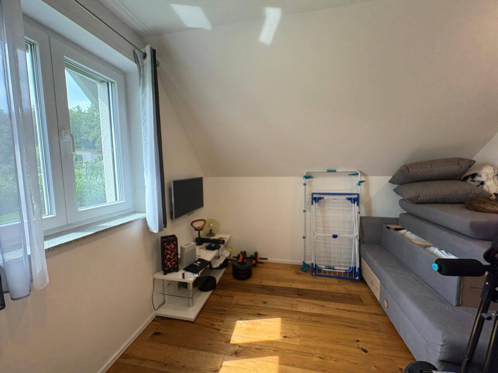 Geräumiges Zimmer mit Holzboden, Fenster und Dachschräge, vielseitig nutzbar.
