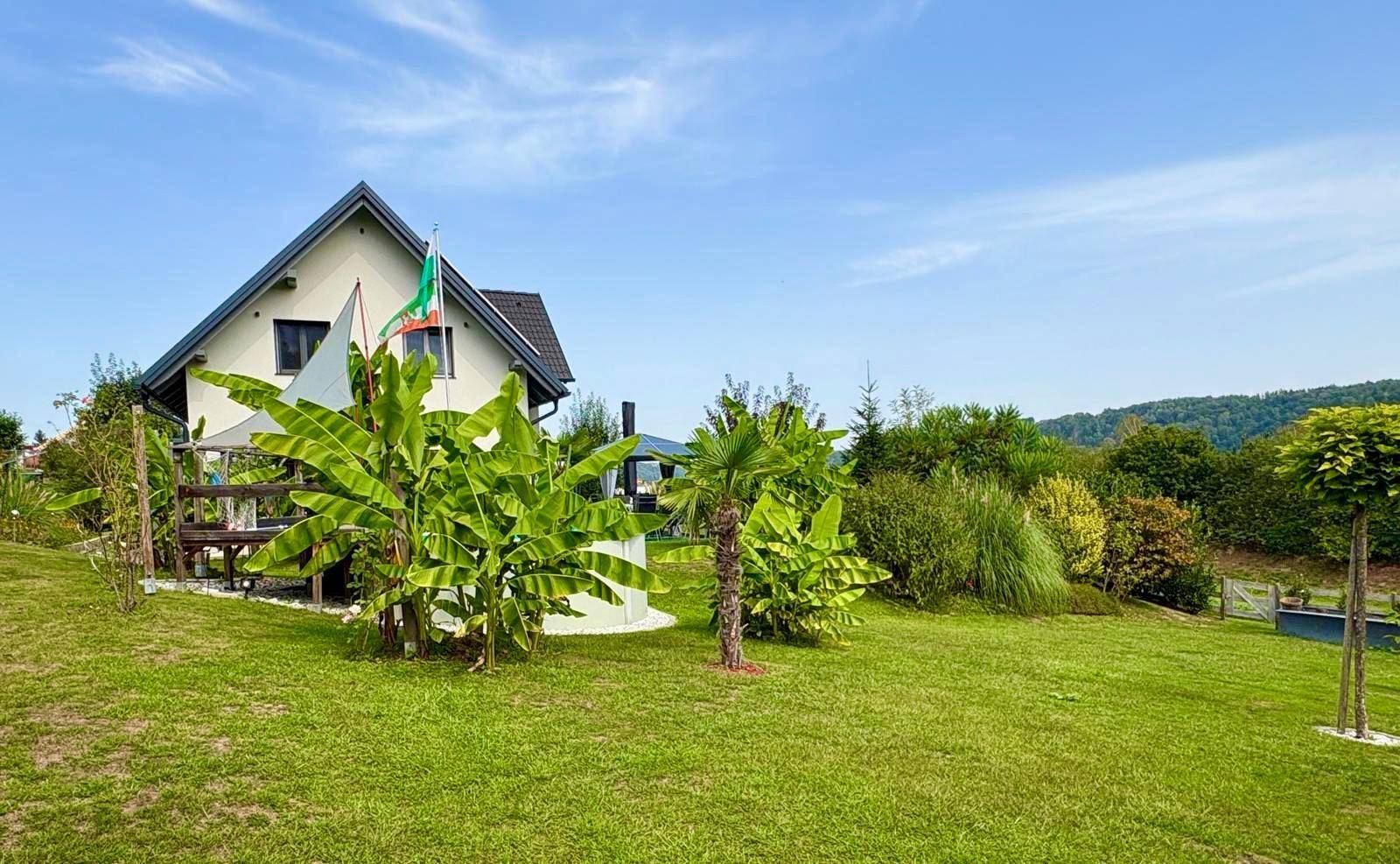 Weitläufiger Garten mit Rasenfläche, tropischen Pflanzen und dem Haus im Hintergrund.