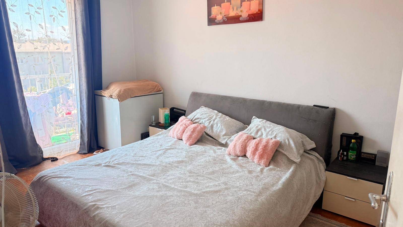 Schlafzimmer mit Doppelbett, zwei Nachttischen und Fenster mit Vorhängen.
