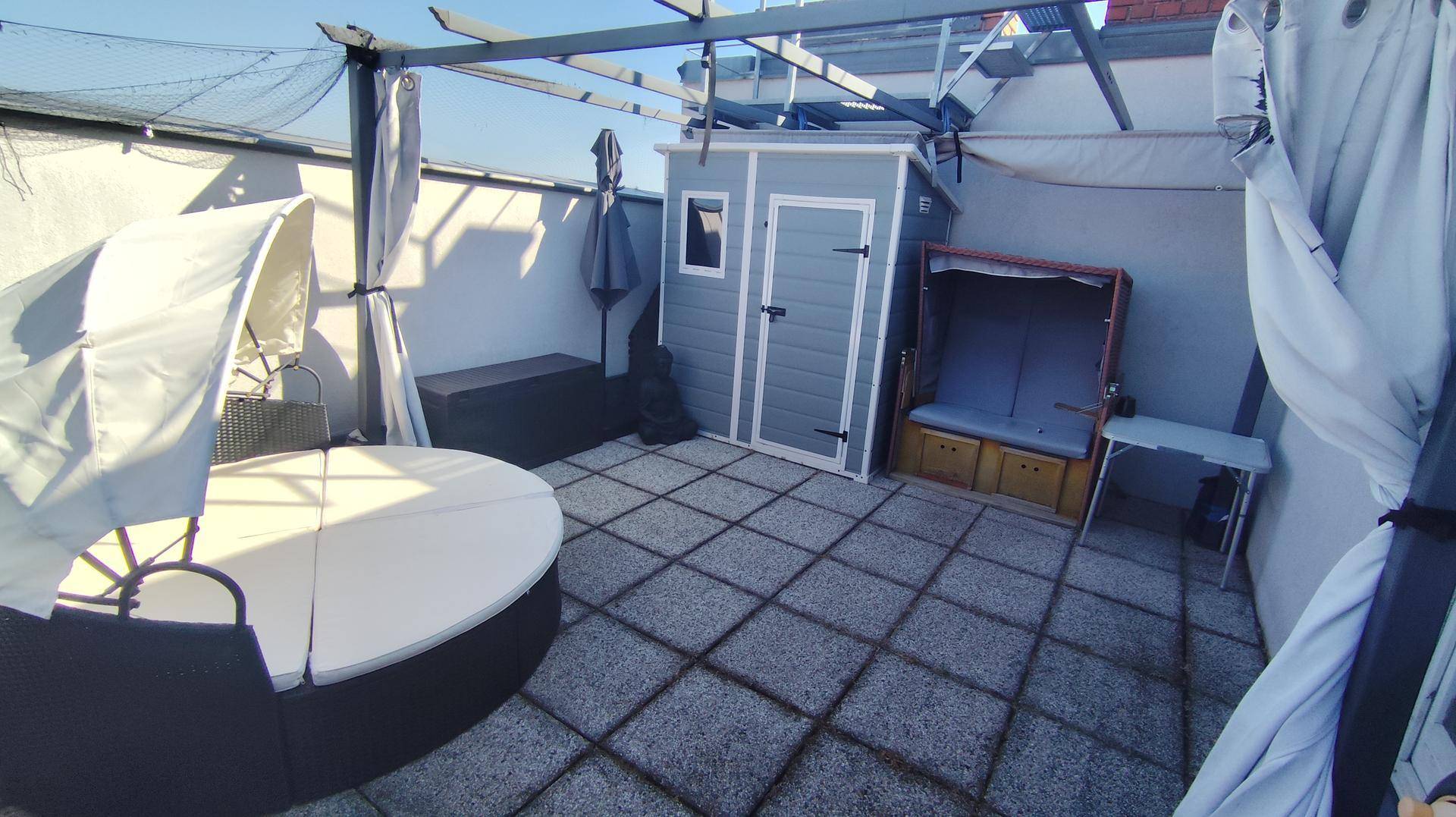 Weitläufige Dachterrasse mit verschiedenen Sitzgelegenheiten und Blick auf die Stadt.