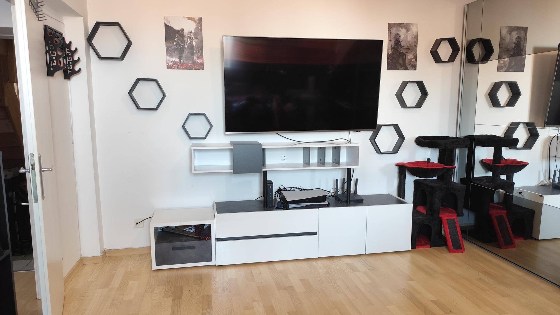 Moderner Wohnbereich mit Fernseher, Mediamöbeln und stilvollen sechseckigen Wanddekorationen.