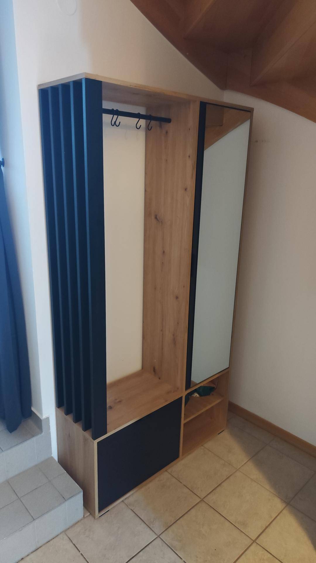 Moderner Garderobenschrank aus Holz mit Spiegel und schwarzen Akzenten im Flur.