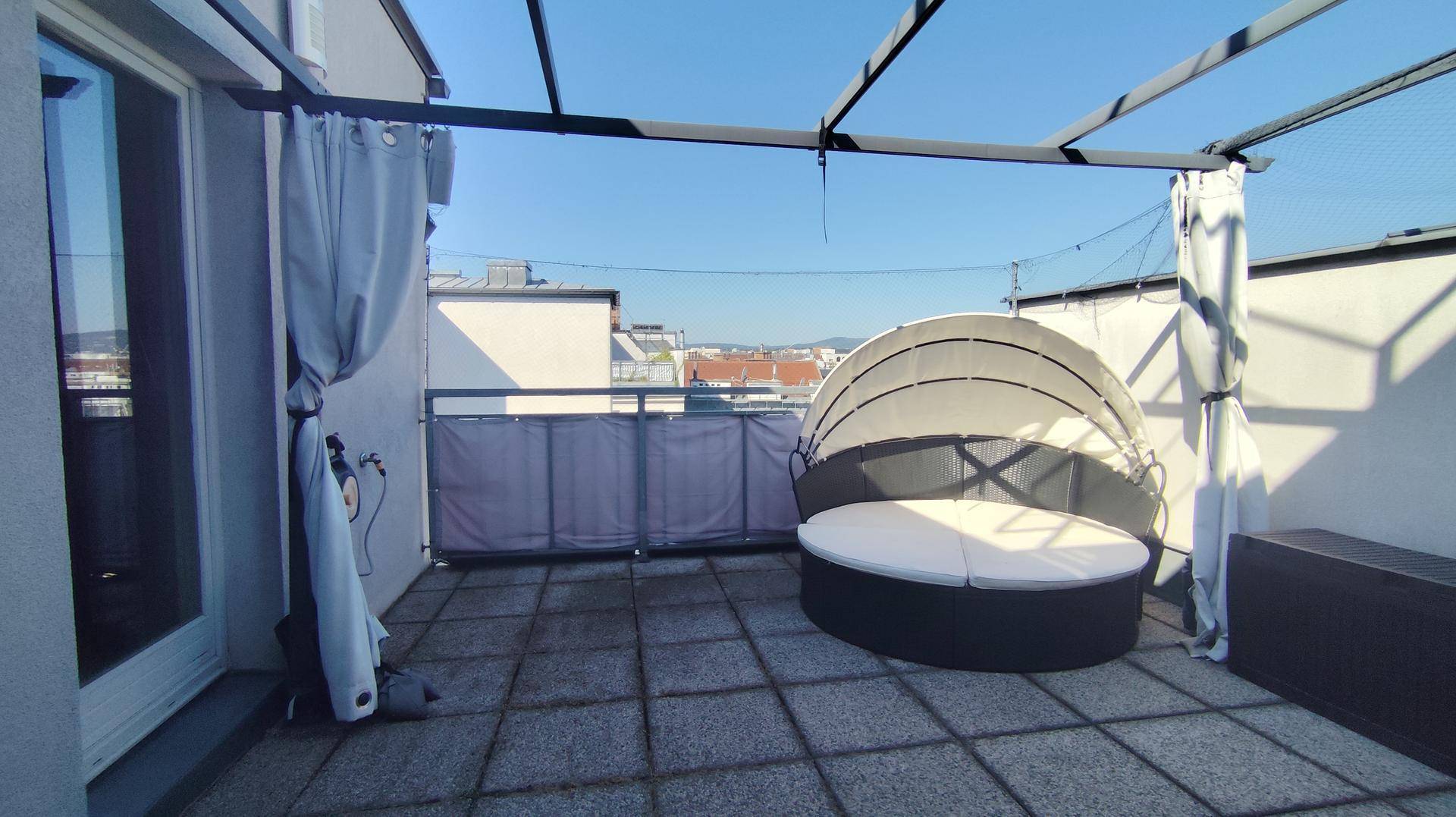 Geräumige Dachterrasse mit Lounge-Möbeln, Pergola und weitem Stadtblick.