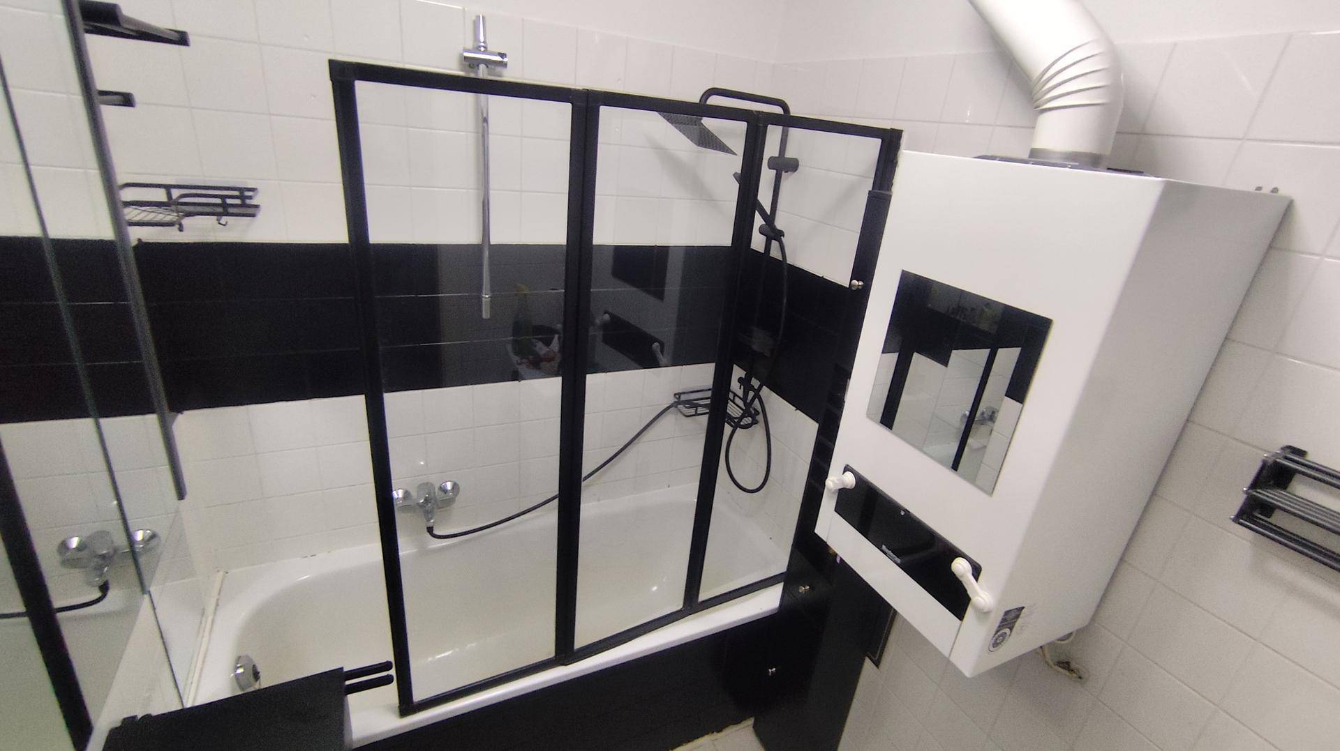 Modernes Badezimmer mit Badewanne, Duschabtrennung und schwarz-weißen Fliesen.