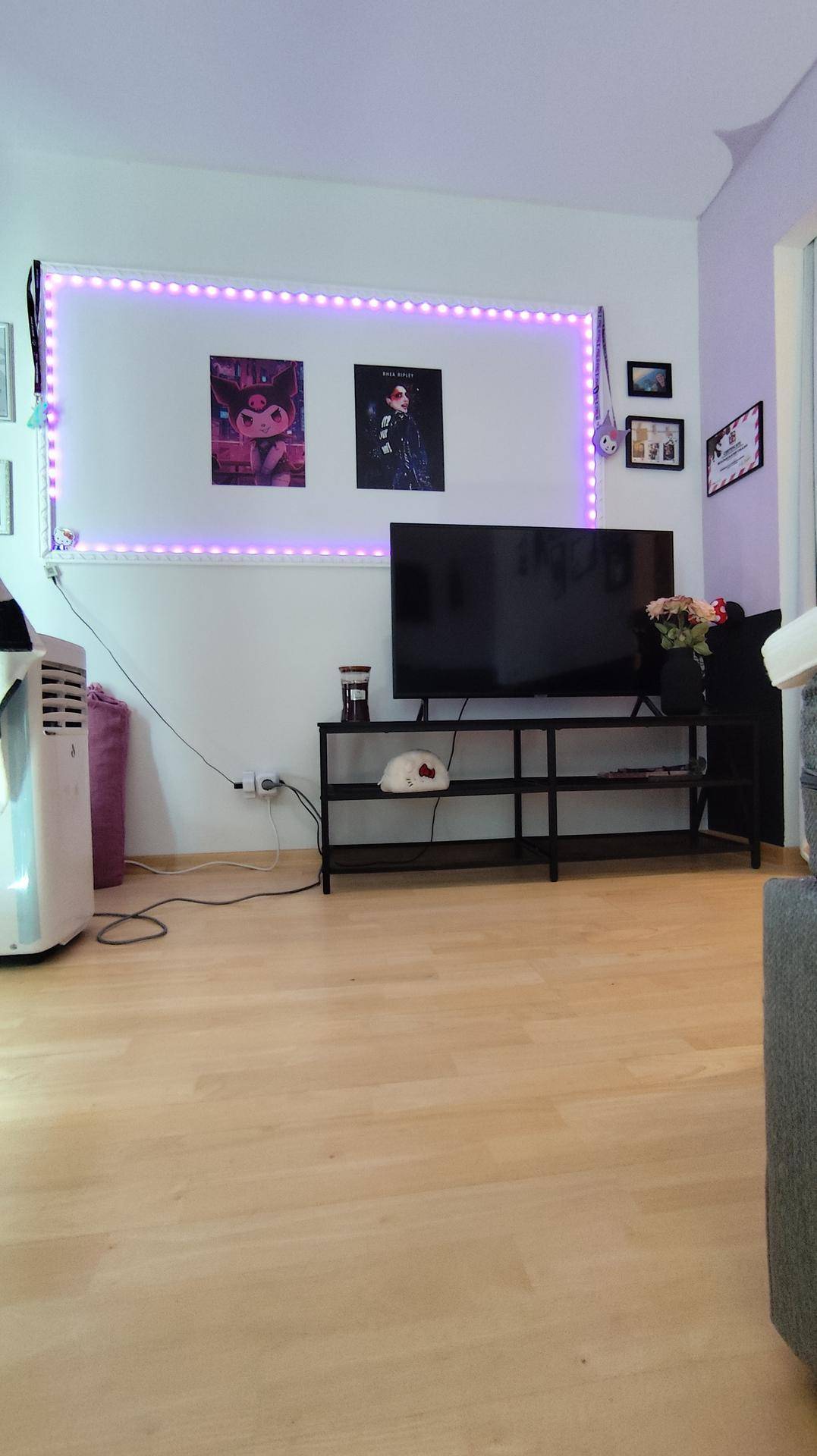 Vielseitiger Raum mit Fernseher, Mediamöbeln und dekorativer LED-Beleuchtung, die eine besondere Atmosphäre schafft.