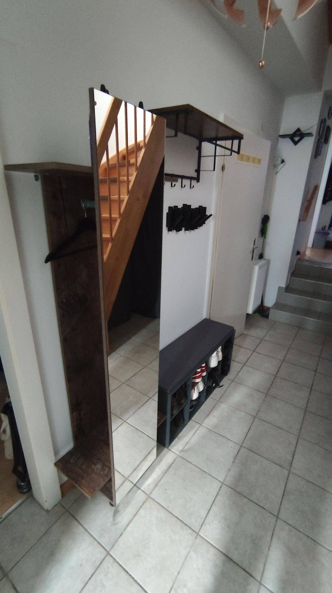 Flur mit großem Spiegel, der die Holztreppe reflektiert, und praktischer Schuhbank.